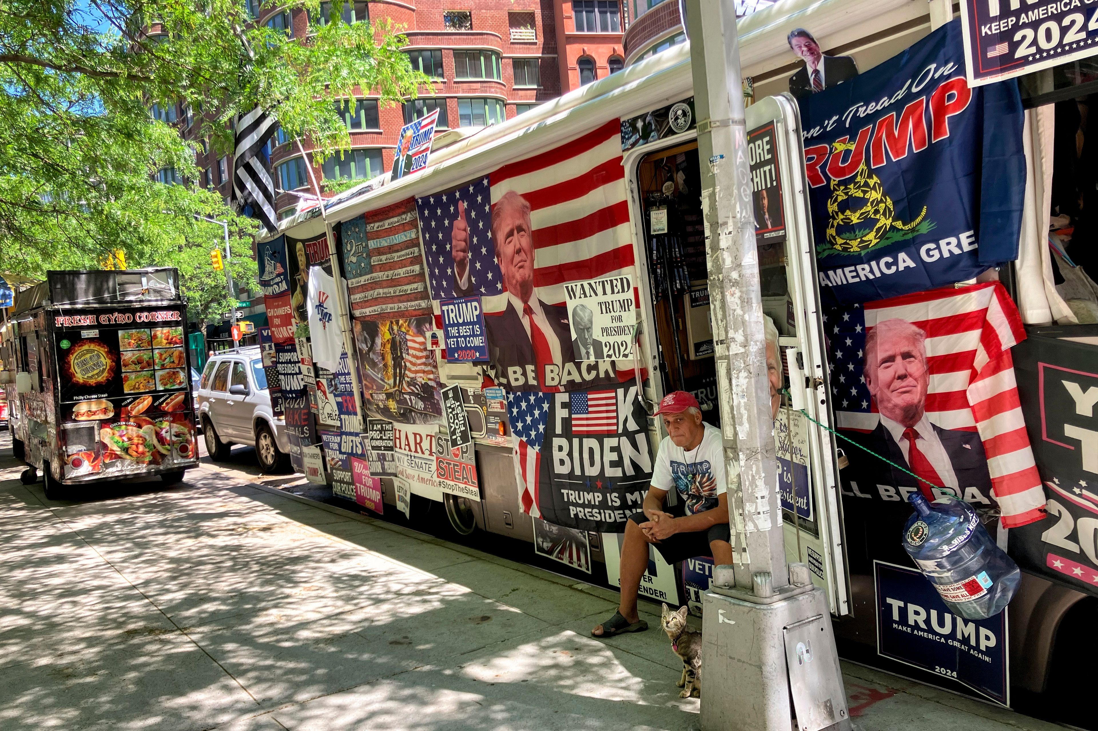 Rocky Granata sits in the doorway of his bus, Friday, May 24, 2024, in New York. Granata and his wife who lived in and sold pro-Donald Trump merchandise out of the bus covered with pro-Trump flags and posters are homeless after the vehicle crashed into several street signs and utility poles on Sunday, June 2.