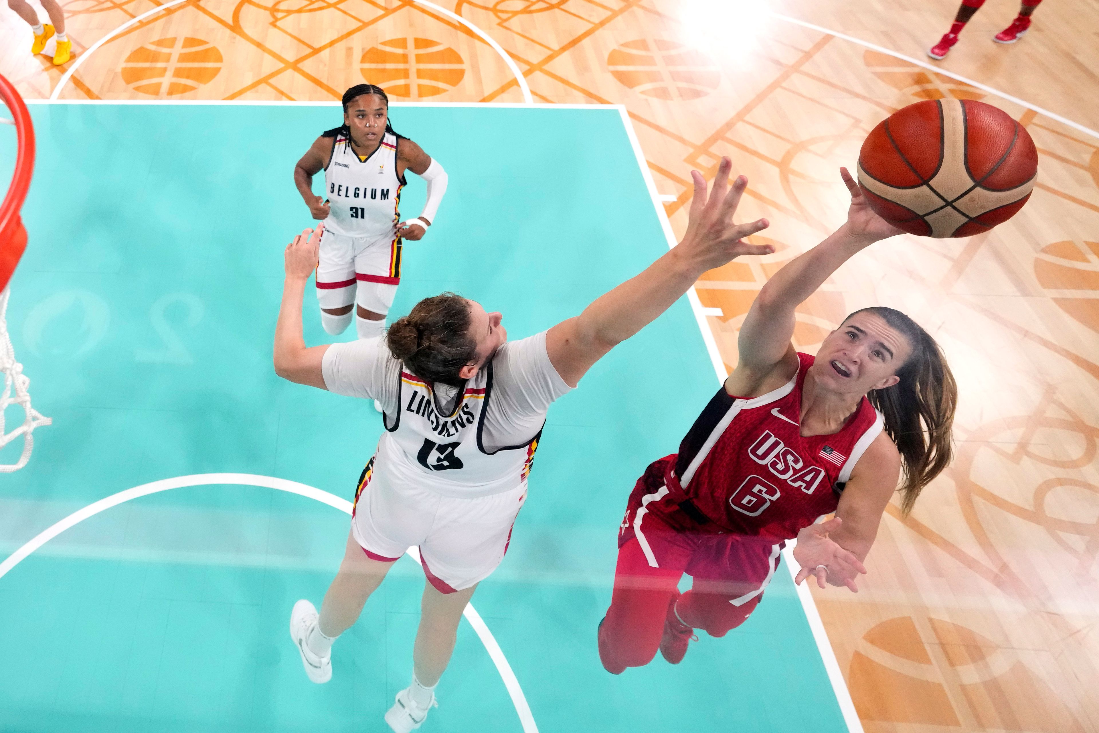 United States' Sabrina Ionescu, right, shoots as Belgium's Kyara Linskens, center, defends in a women's basketball game at the 2024 Summer Olympics, Thursday, Aug. 1, 2024, in Villeneuve-d'Ascq, France. (AP Photo/Michael Conroy, Pool)