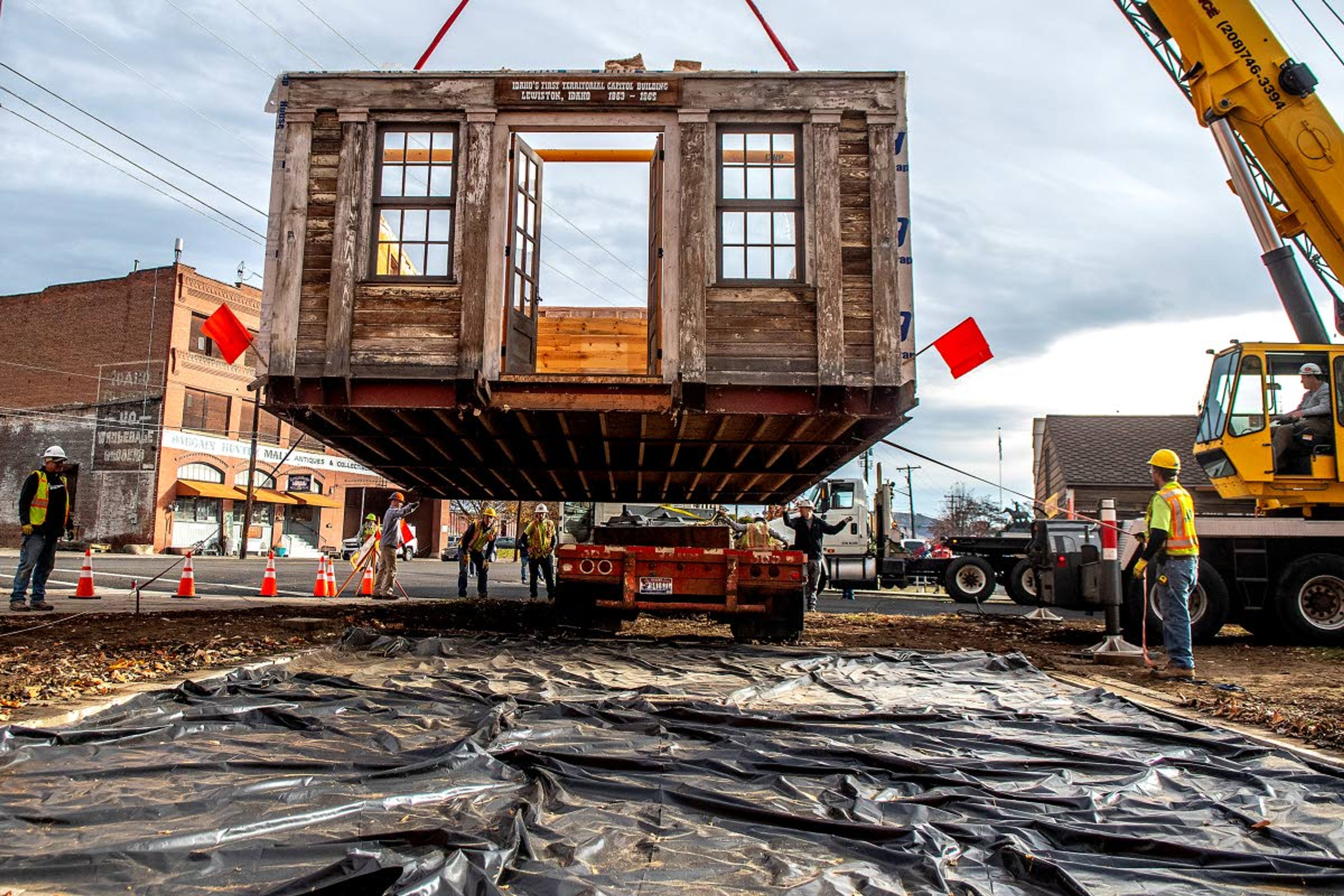 After its roof had been temporarily removed, the Idaho Territorial Capitol building is lifted up by a crane while a flatbed truck stands by to move the replica structure to its new location at the Nez Perce County Historical Society and Museum on Tuesday morning.