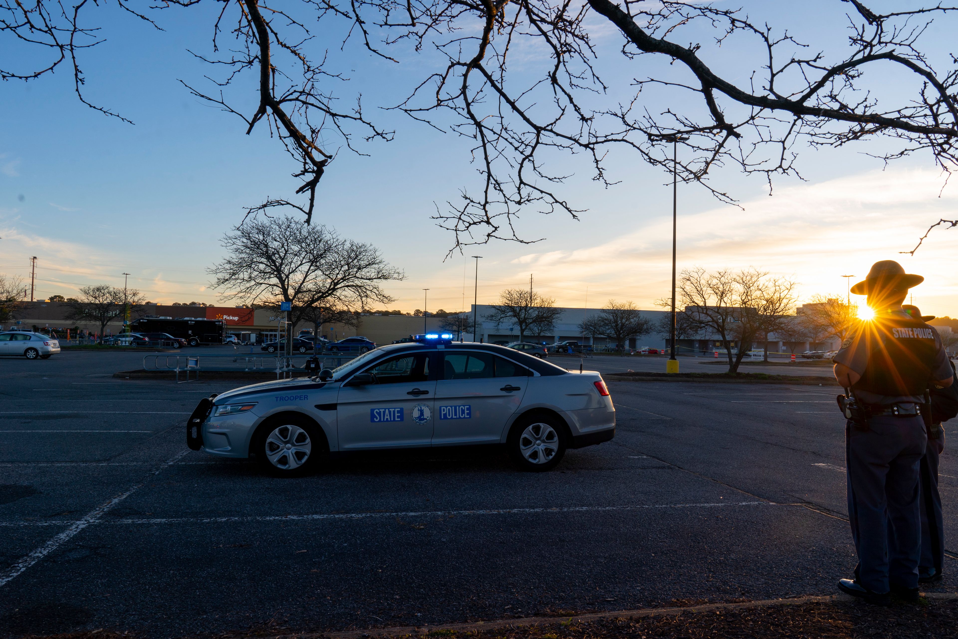 The sun rises behind two Virginia State Troopers as law enforcement works the scene of a mass shooting at a Walmart, Wednesday, Nov. 23, 2022, in Chesapeake, Va. The store was busy just before the shooting Tuesday night with people stocking up ahead of the Thanksgiving holiday. (AP Photo/Alex Brandon)