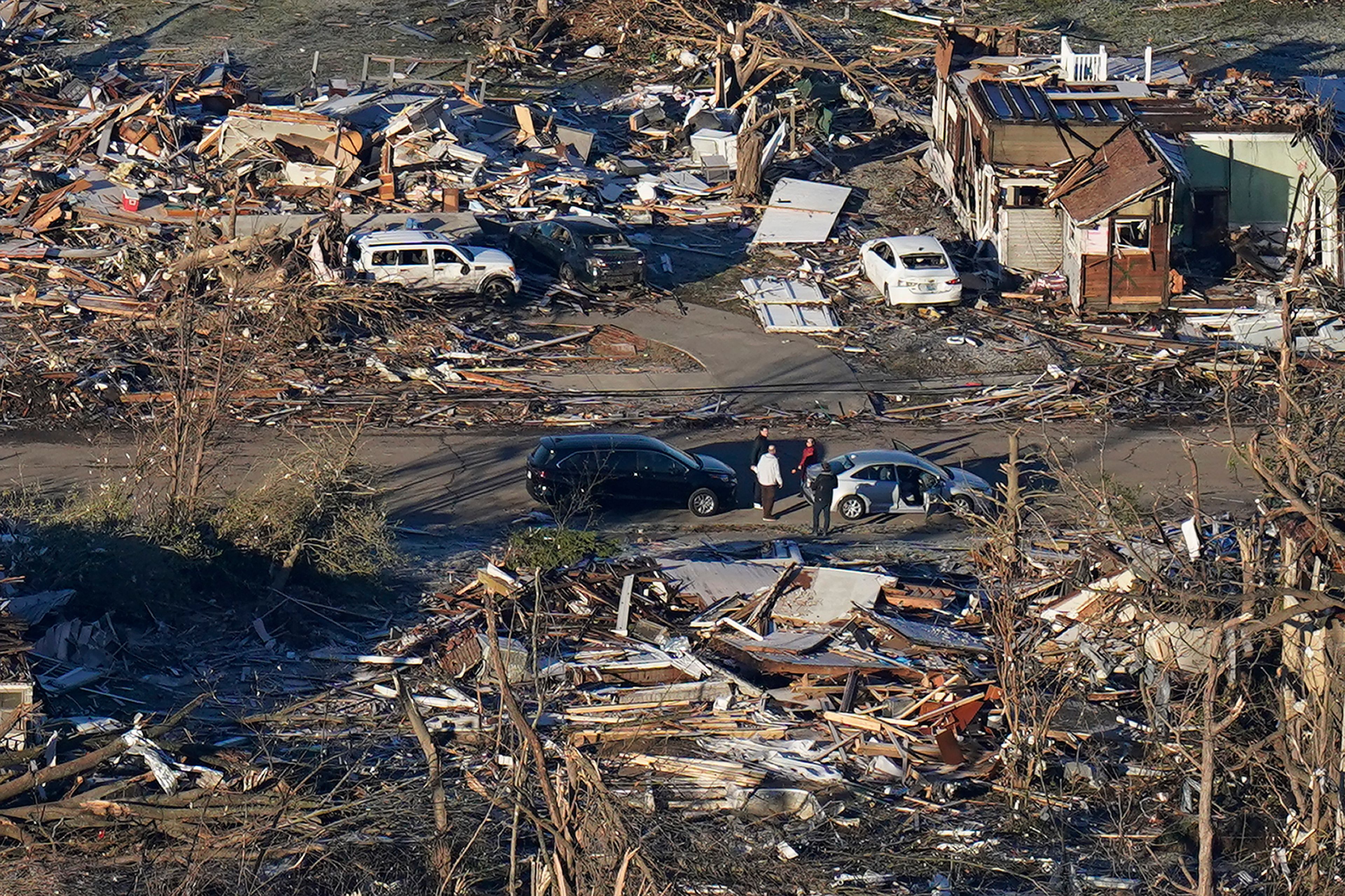 FILE - In a view from this aerial photo, people stand amidst destruction from a tornado in downtown Mayfield, Ky., on Dec. 12, 2021. Kentucky Gov. Andy Beshear says a rental housing shortage has gnawed at him since the recovery began from a tornado outbreak that hit western Kentucky in 2021. On Monday, June 3, 2024, Beshear unveiled plans to build 953 rental housing units in four counties — Christian, Graves, Hopkins and Warren.