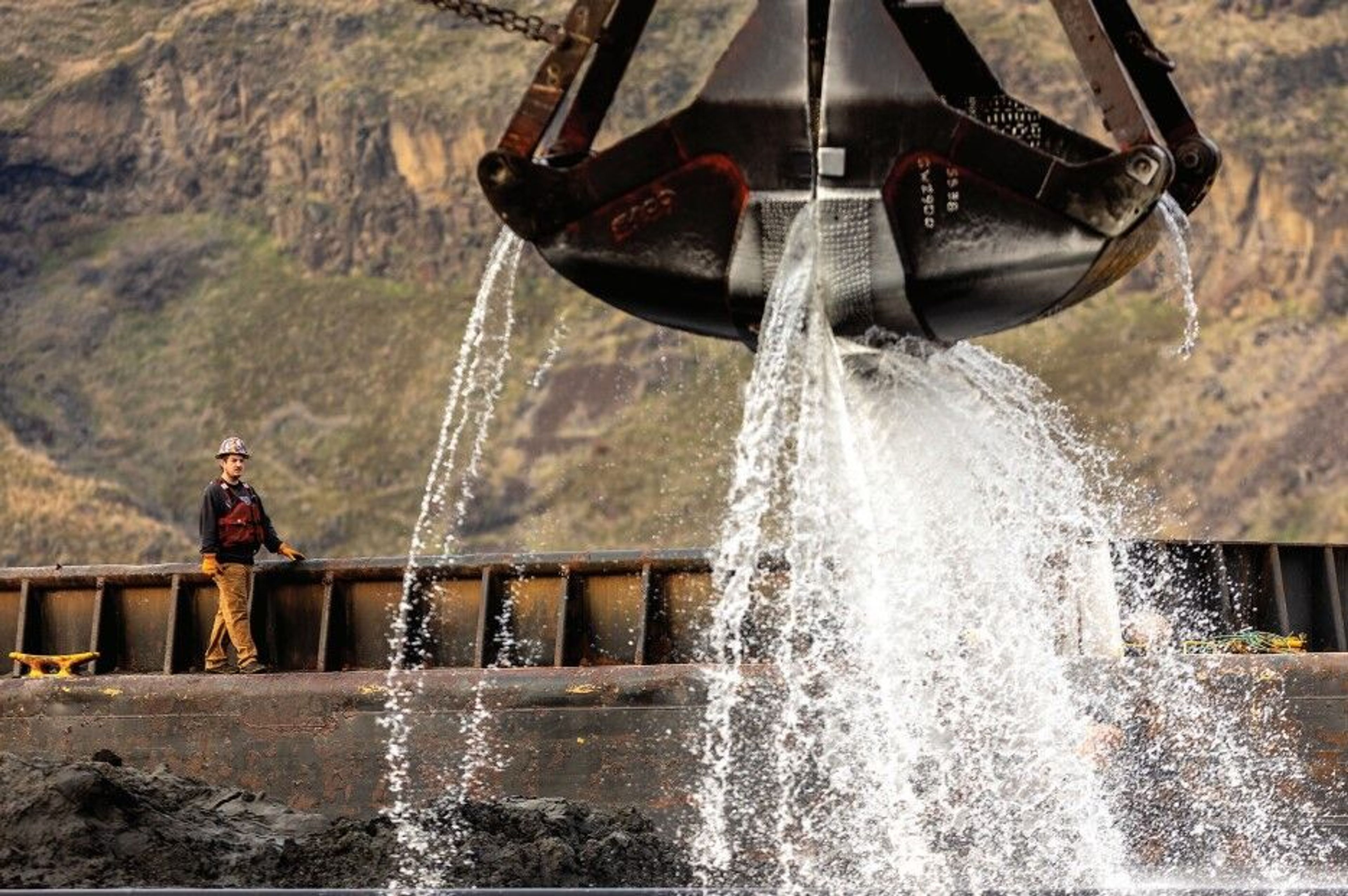 A worker walks across a barge as a water falls from a crane as HME Construction, contracted by the U.S. Army Corp of Engineers, continues work Tuesday to dredge the Snake River. The process removes sediment and debris from the bottom of the river.