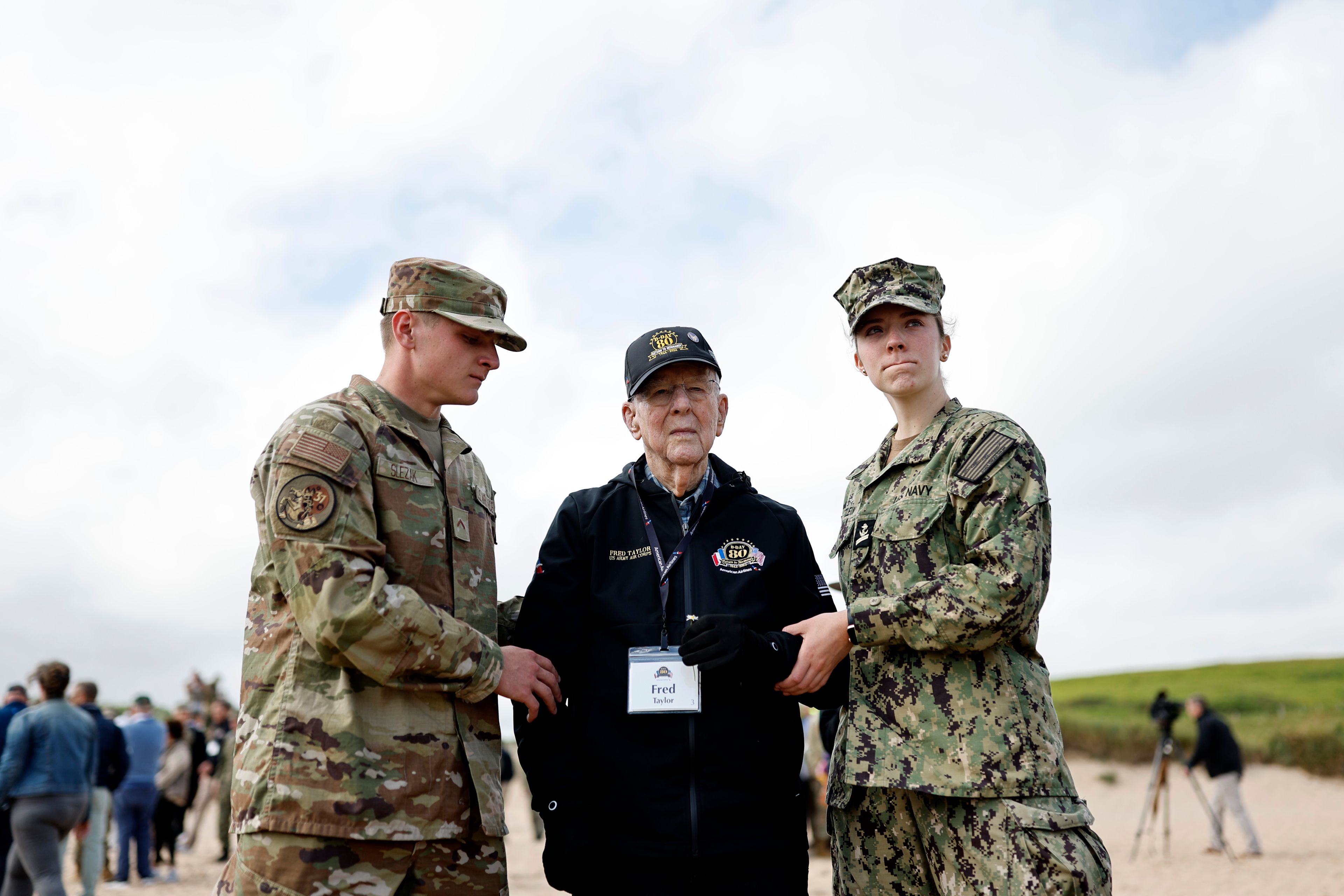 US soldiers assist American WWII veteran Fred Taylor during a ceremony on Omaha Beach, Tuesday, June 4, 2024 in Normandy. World War II veterans from across the United States as well as Britain and Canada are in Normandy this week to mark 80 years since the D-Day landings that helped lead to Hitler's defeat. (AP Photo/Jeremias Gonzalez)