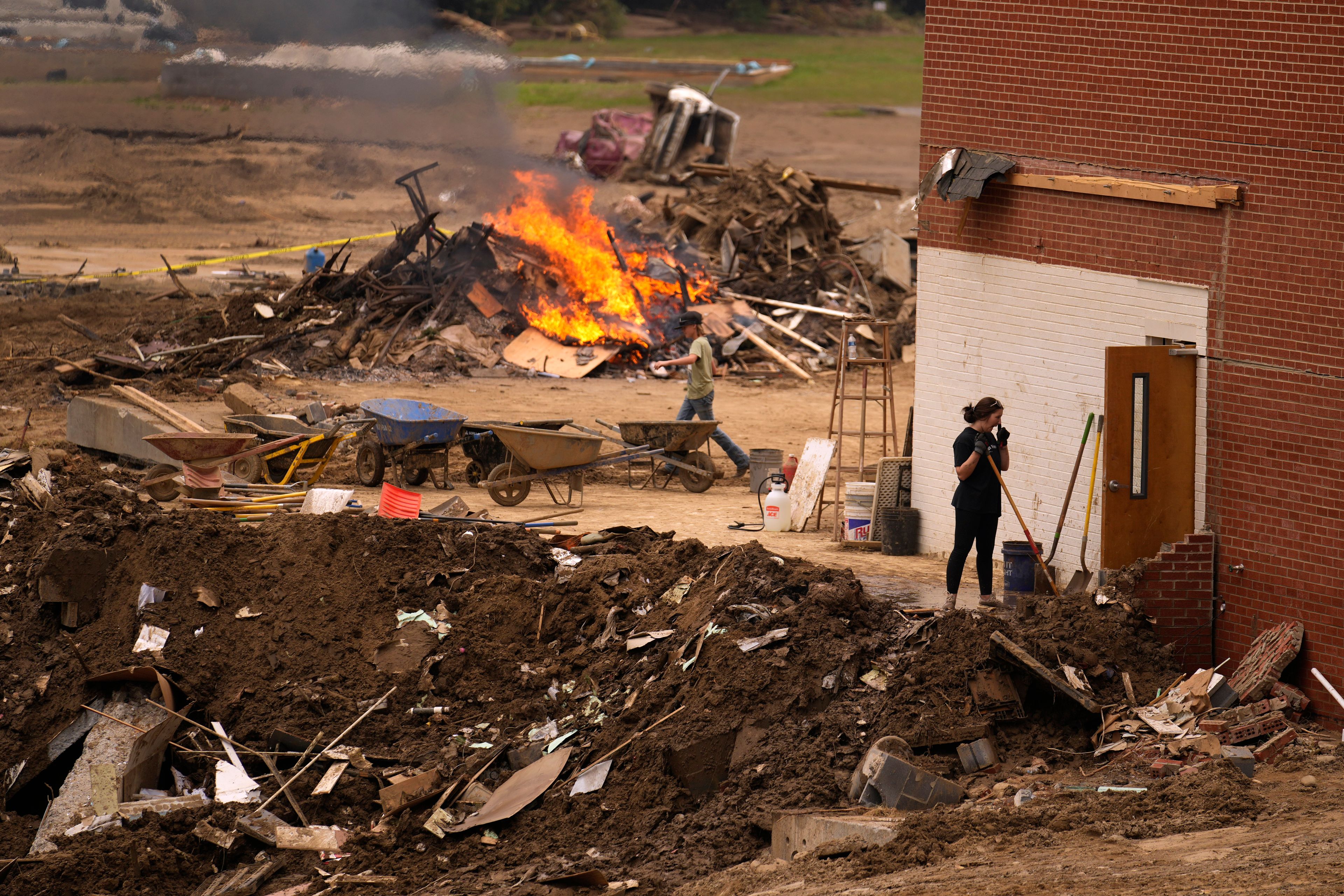 People clean up and burn debris left in the aftermath of Hurricane Helene Friday, Oct. 4, 2024, in Erwin, Tenn. (AP Photo/Jeff Roberson)