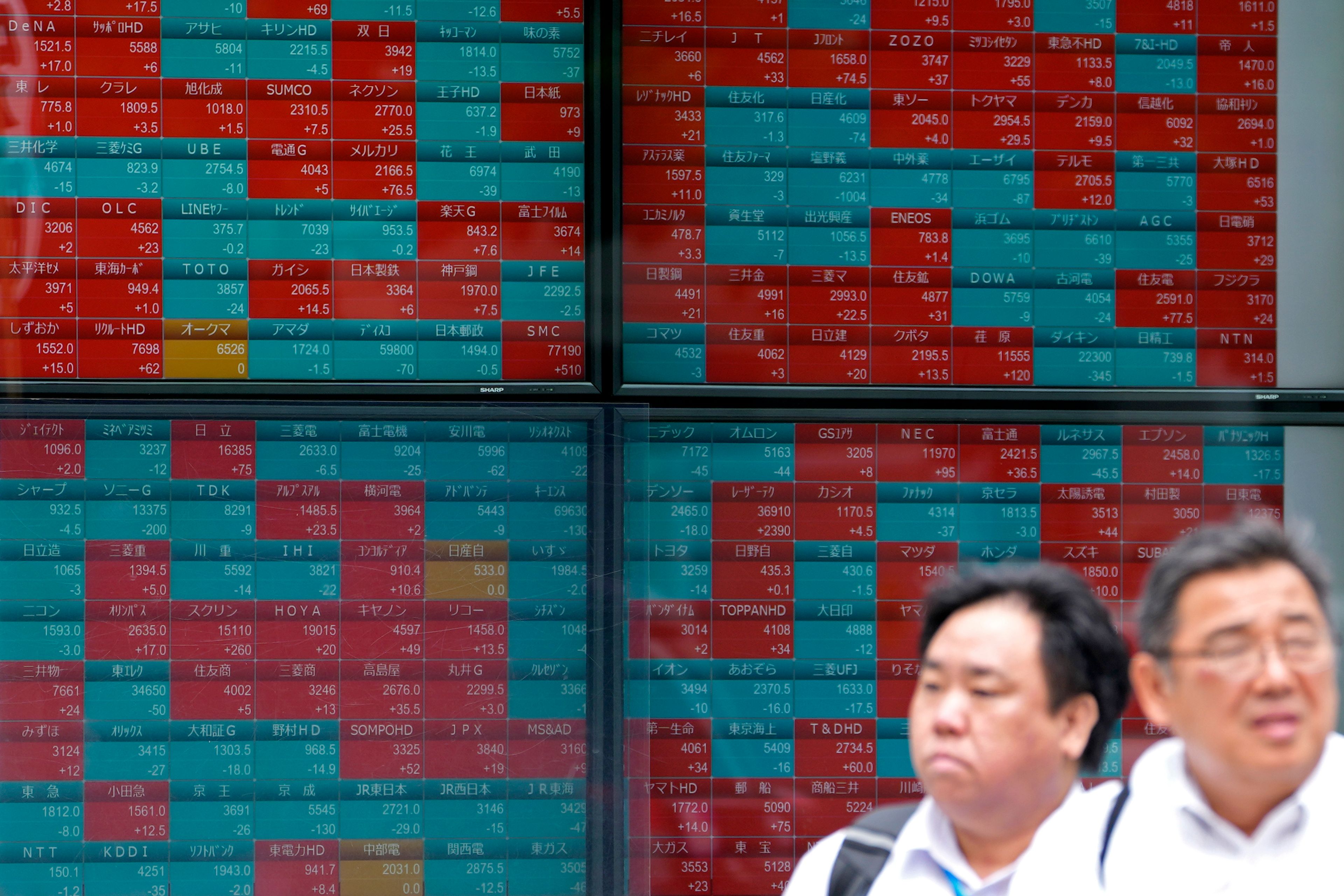 People move past an electronic stock board showing Japan's stock prices outside a securities firm Friday, June 7, 2024 in Tokyo.