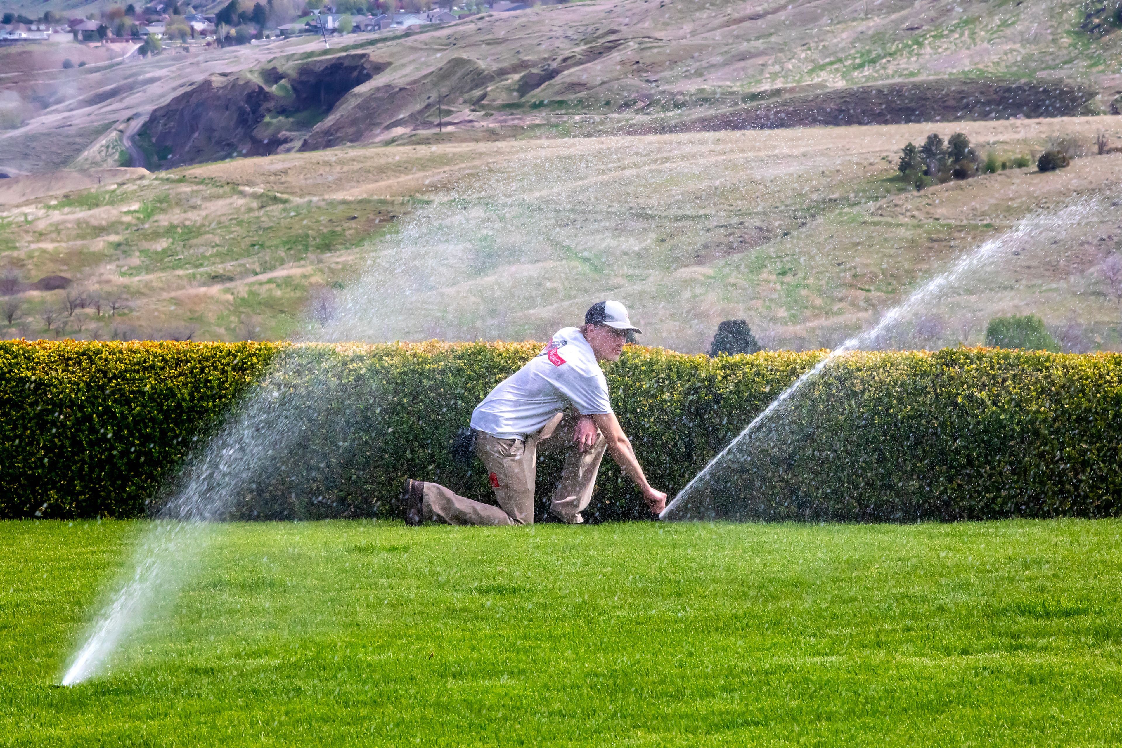 Cade McKarcher adjusts a sprinkler as his father Brian McKarcher’s home on Thursday.