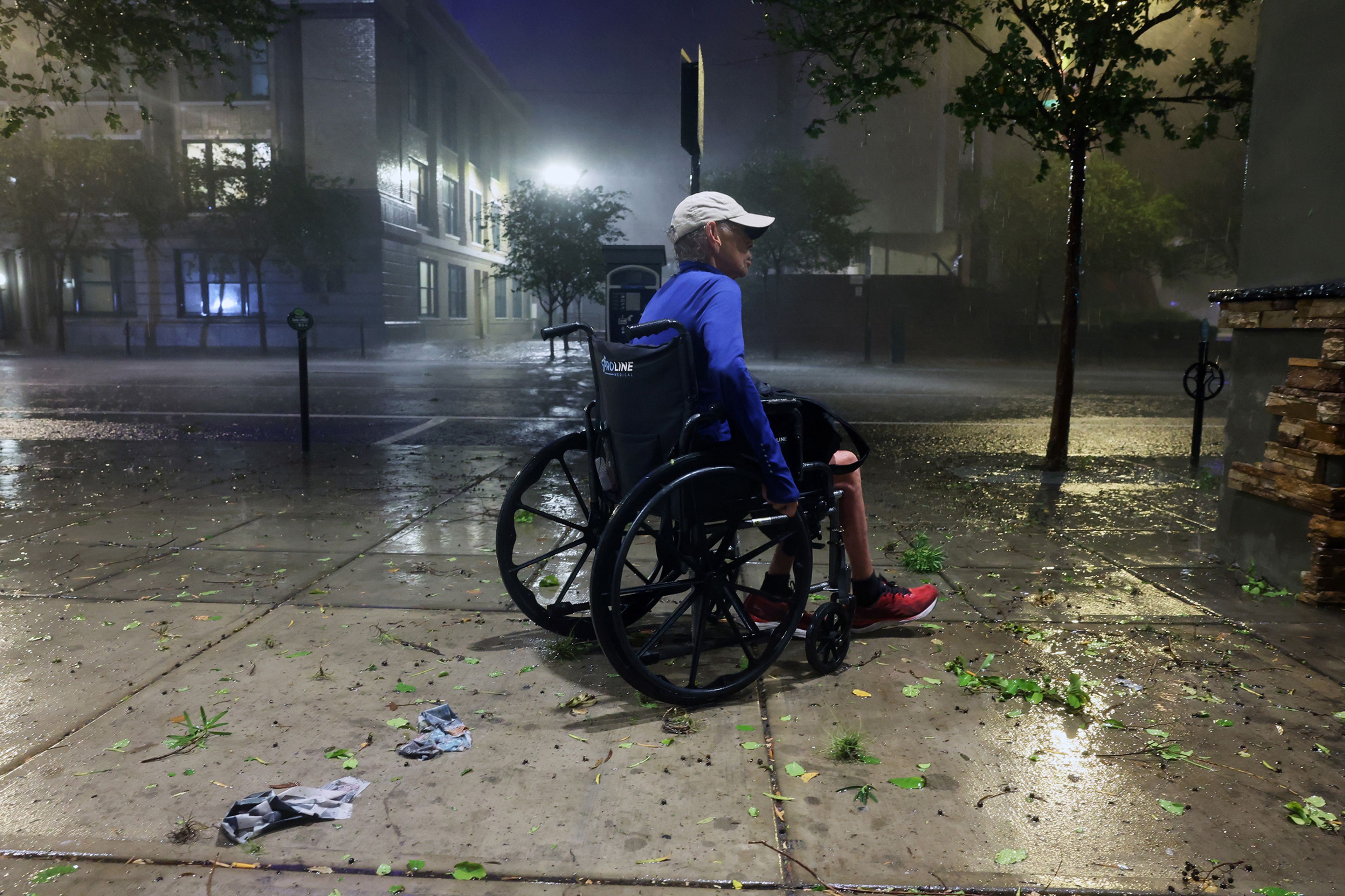 A woman in a wheelchair makes her way along a downtown sidewalk as Hurricane Milton makes landfall on Oct. 9, 2024, in Tampa, Florida.  (Spencer Platt/Getty Images/TNS),