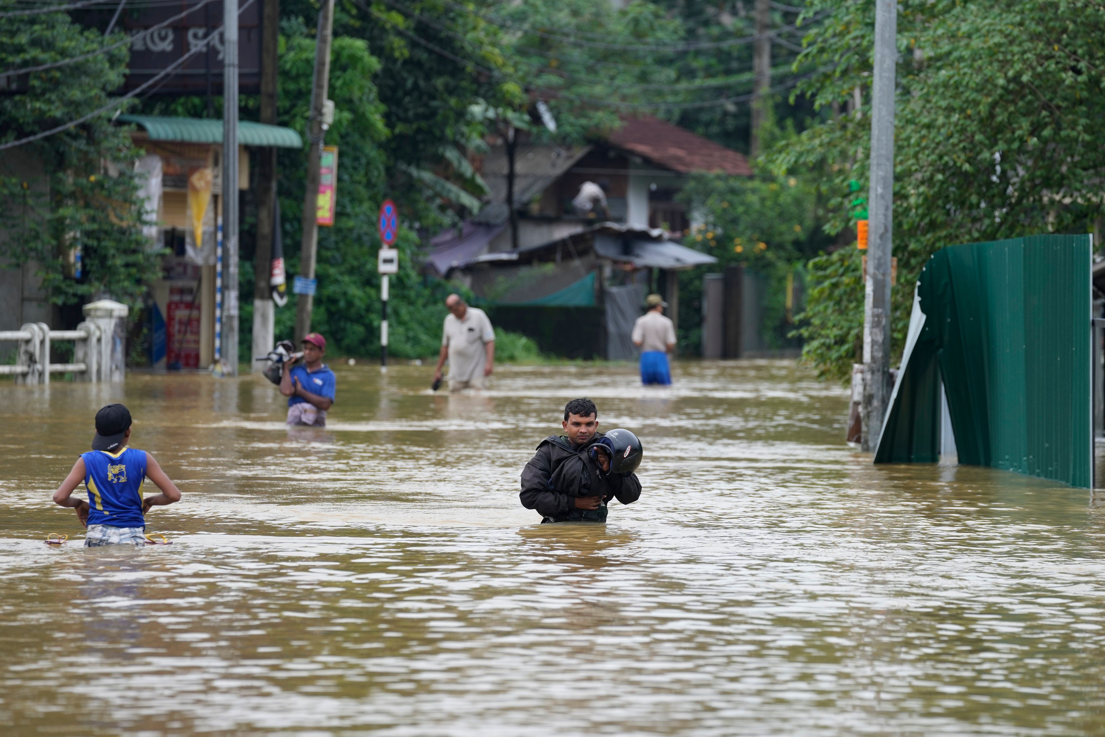 People wade through flood waters in Kelaniya, a suburb of Colombo, Sri Lanka, Monday, June 3, 2024. Sri Lanka closed schools on Monday as heavy rains triggered floods and mudslides in many parts of the island nation, killing at least 10 people while six others have gone missing, officials said.