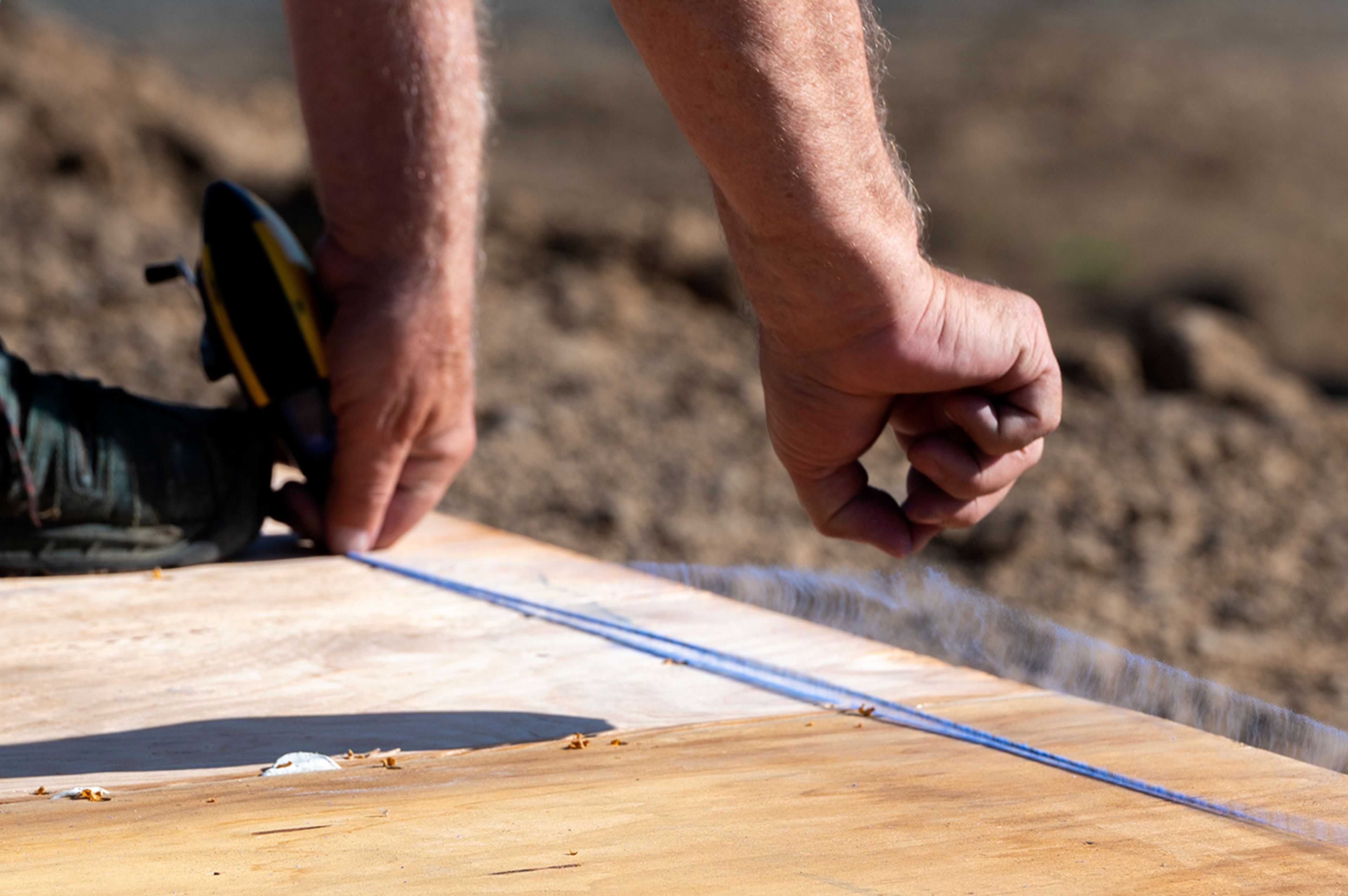 A volunteer from Palouse Habitat for Humanity snaps a chalk string line while raising a wall for a home being constructed on Leepike Court in Moscow.