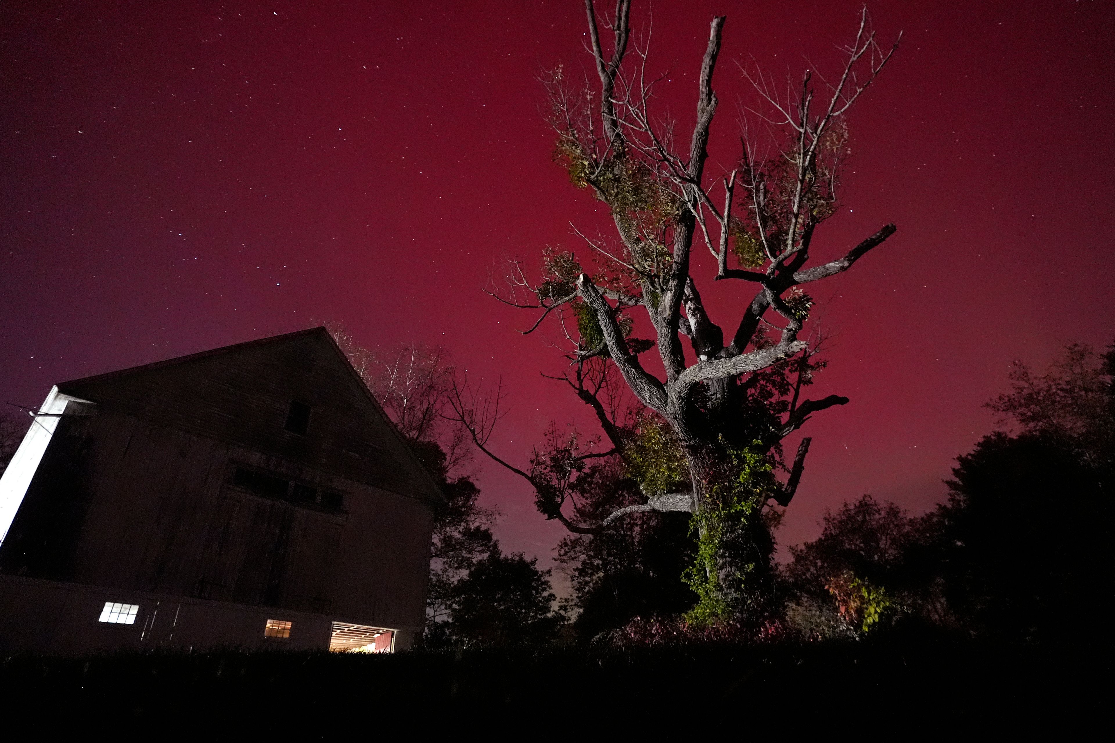 An aurora borealis, also known as the northern lights, glows red in the sky above a barn, Thursday, Oct. 10, 2024, in East Derry, N.H. (AP Photo/Charles Krupa)