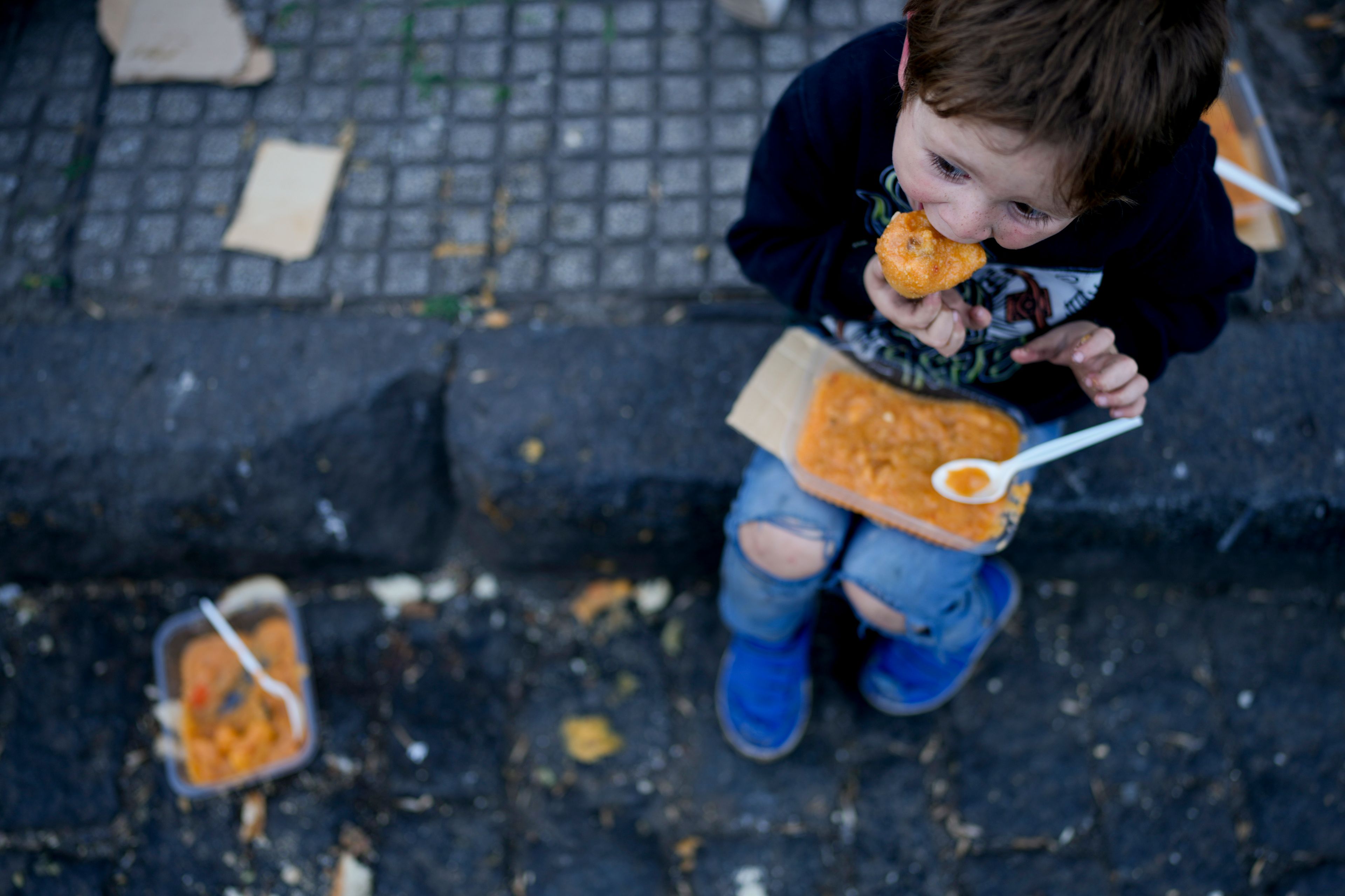 A child eats a free, hot meal on the curb of a soup kitchen on the outskirts of Buenos Aires, Argentina, Thursday, Sept. 12, 2024. (AP Photo/Natacha Pisarenko)