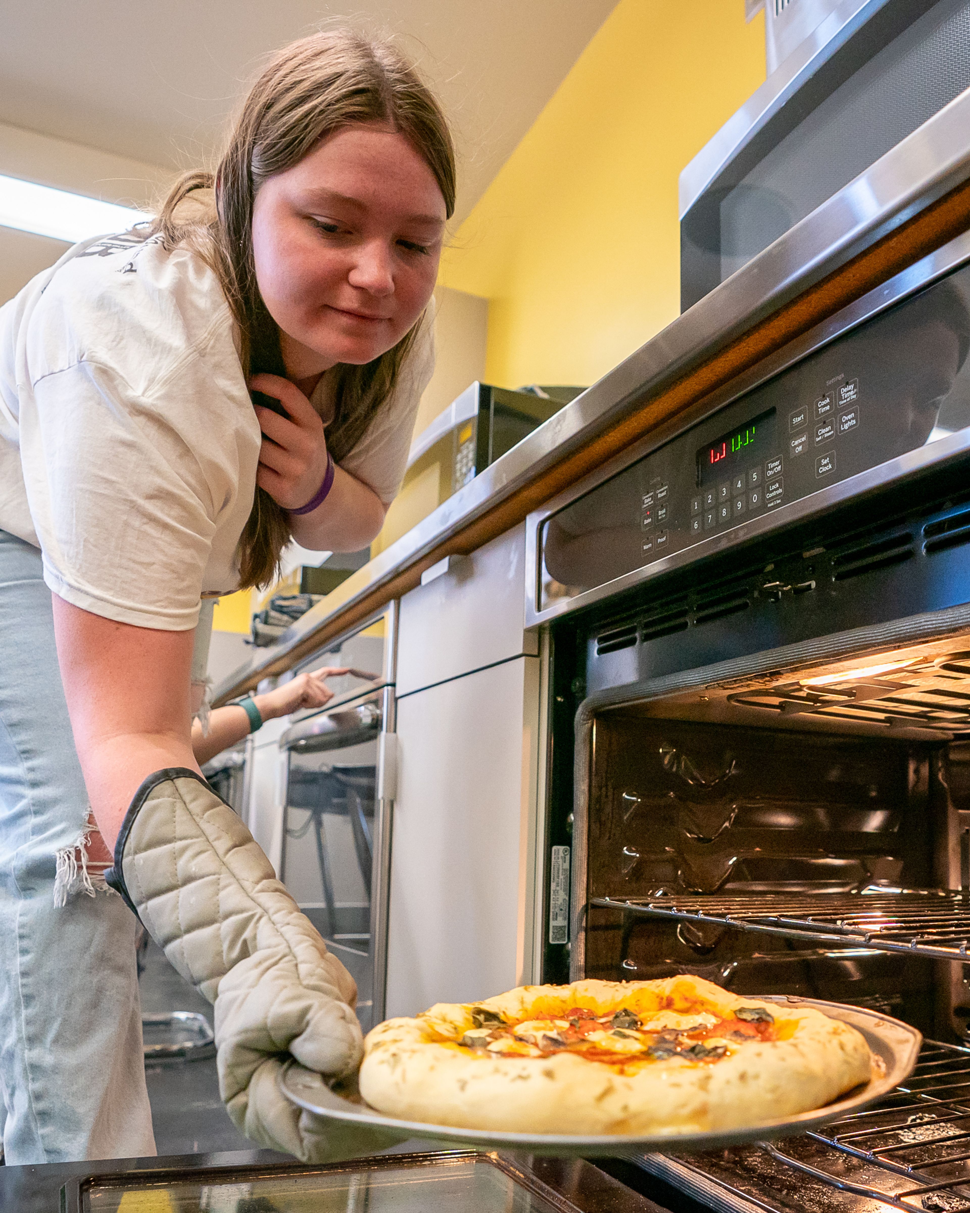 Hannah Wlash, 16, of Kellogg, takes her margarita pizza out of the oven during the final day of the 2023 Pizza-ology Camp on Wednesday at the Carmelita Spencer Food Laboratory in Moscow.