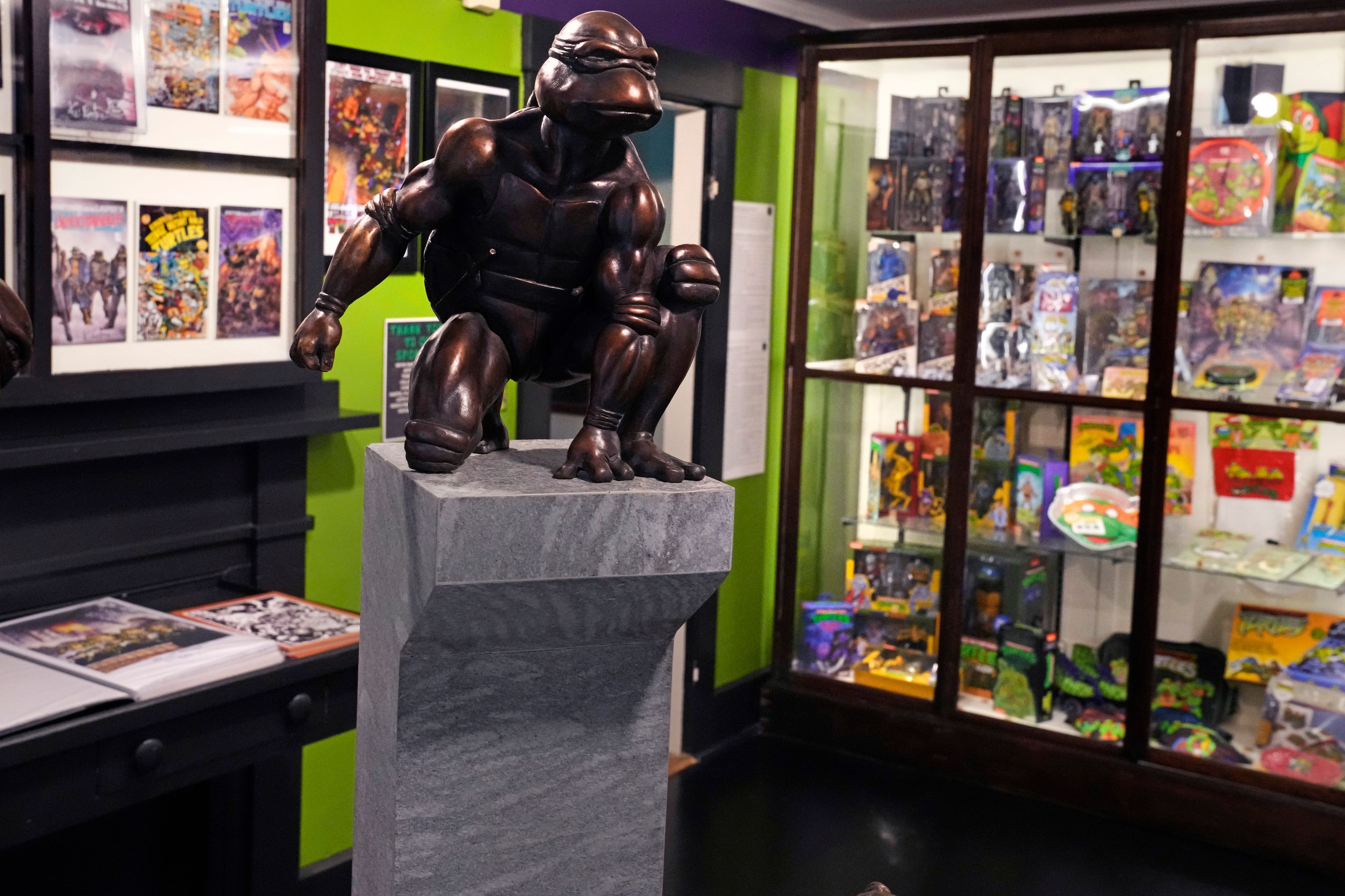 A bronze sculpture of the Teenage Mutant Ninja Turtle character "Raphael" is displayed along with comic books and memorabilia in a permanent collection at the Woodman Museum, Thursday, Sept. 5, 2024, in Dover, N.H.