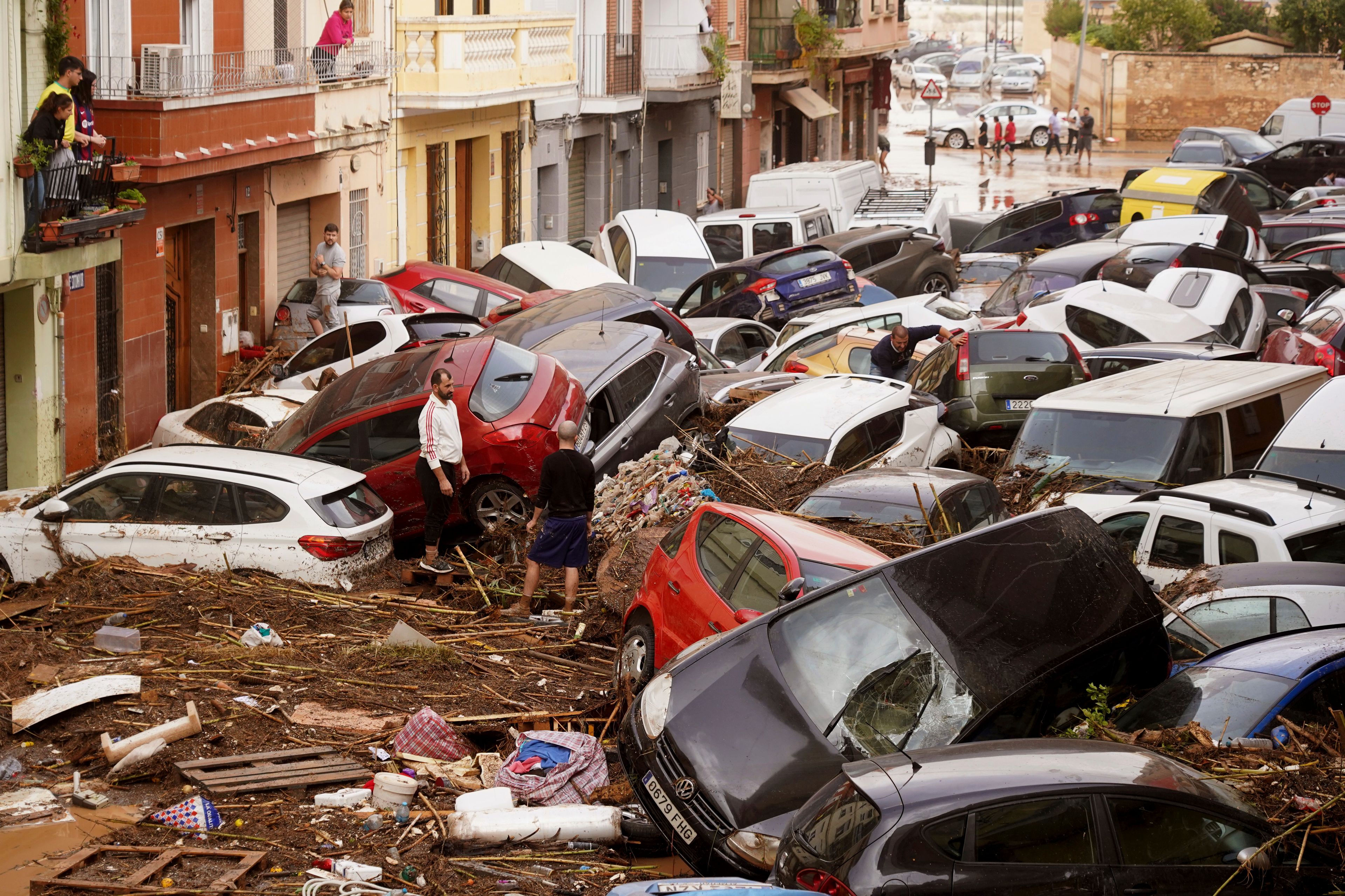 Residents look at cars piled up after being swept away by floods in Valencia, Spain, Wednesday, Oct. 30, 2024. (AP Photo/Alberto Saiz)