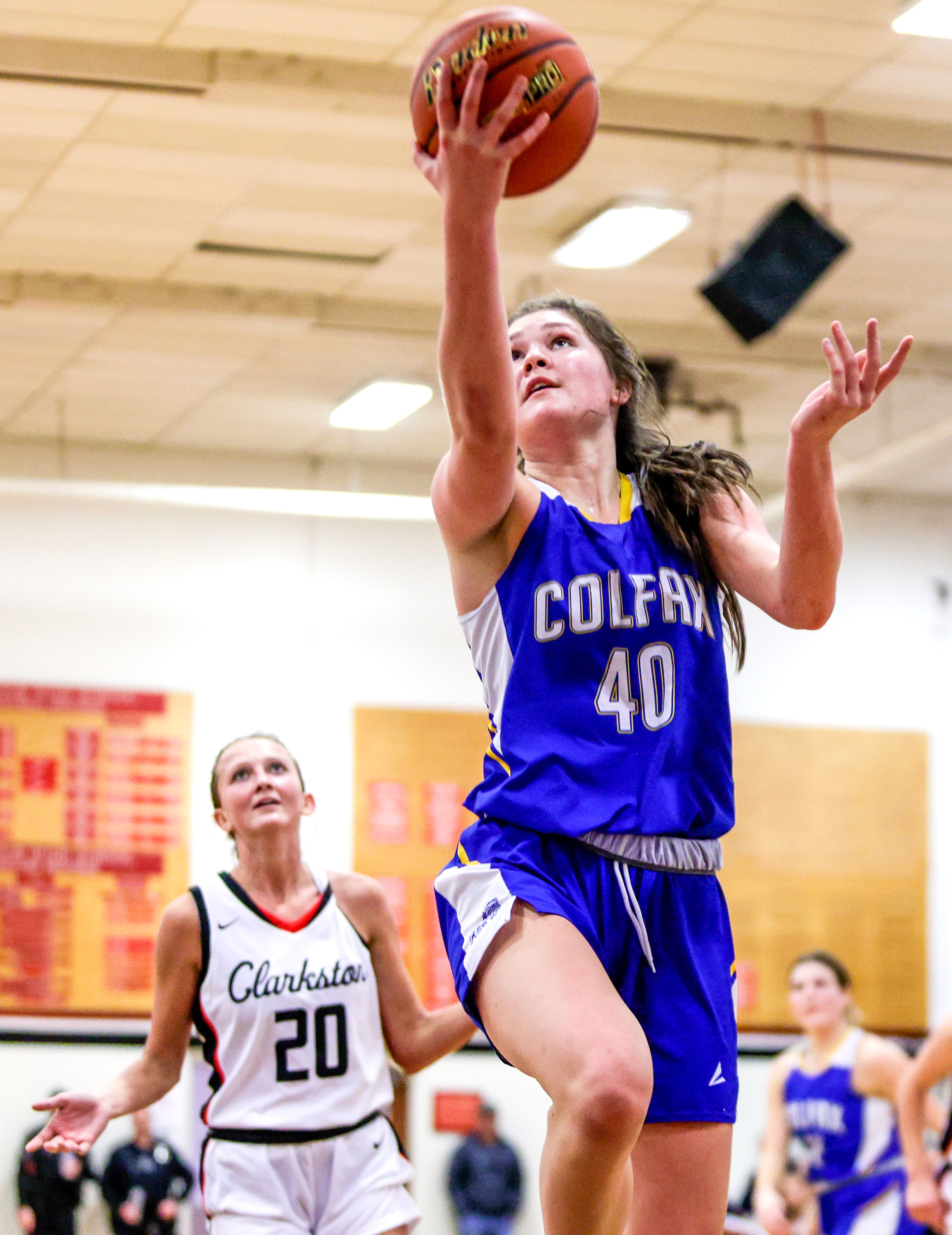 Colfax post Brynn McGaughy leaps up for a shot as Clarkston wing Eloise Teasley reacts behind her during a game Dec. 8, 2022, in Clarkston.