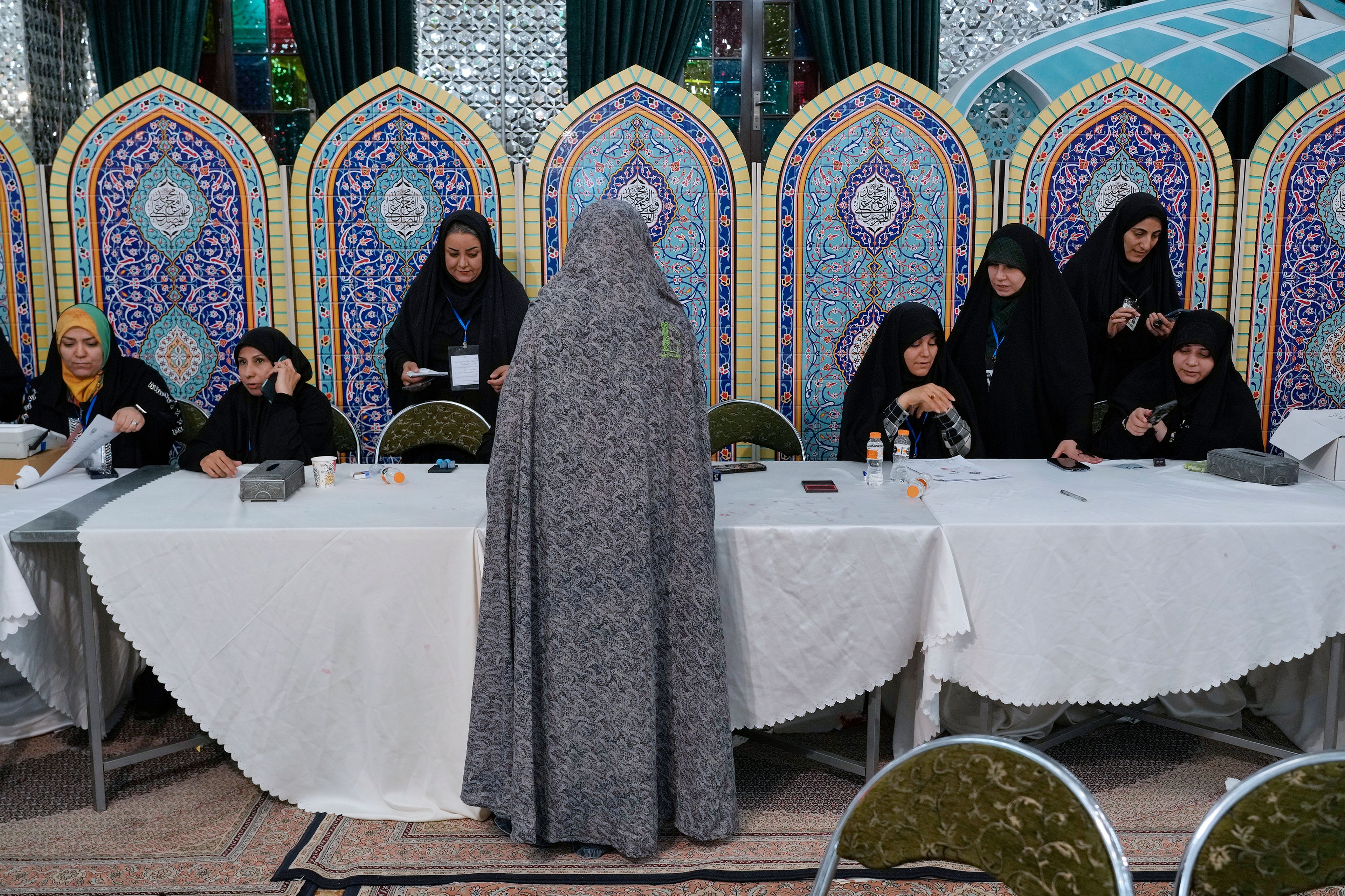 A woman gets her ballot to vote for the presidential election in a polling station at the shrine of Saint Saleh in northern Tehran, Iran, early Saturday, July 6, 2024. Iran held a runoff presidential election on Friday that pitted a hard-line former nuclear negotiator against a reformist lawmaker. (AP Photo/Vahid Salemi)