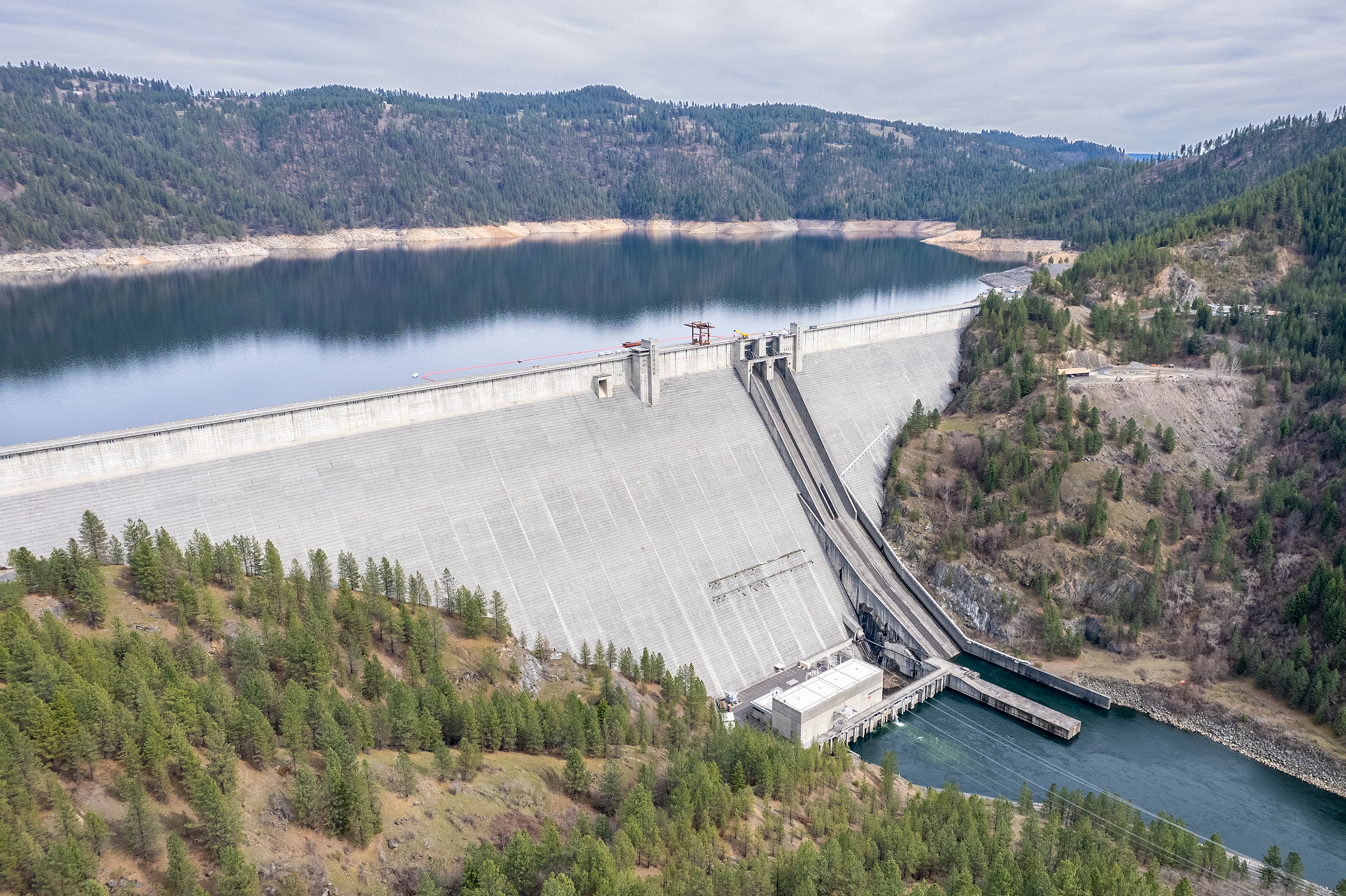 TOP: This photo taken with a drone shows Dworshak Dam and Reservoir near Orofino. ABOVE: Marcia Trussell, left, keeps ahold of her fishing pole as Ted Mordhorst goes in with the net as they work to land a steelhead on the North Fork of the Clearwater River near Dworshak Dam in February 2021 in Ahsahka. After the steelhead swam back out, Trussell was able to bring it back into shore a second time where Mordhorst successfully netted the fish, which measured 36 inches.