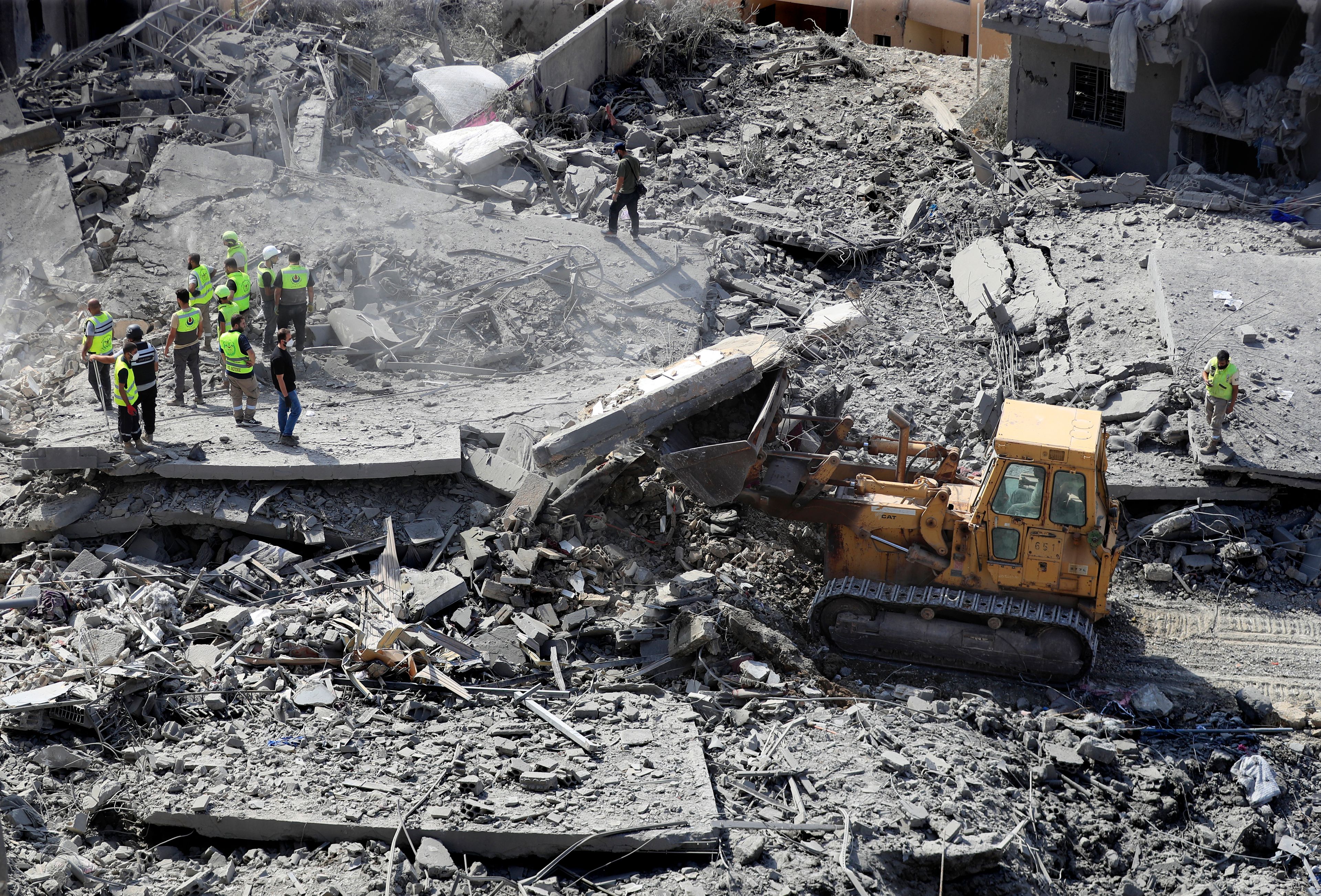 Rescue workers use a bulldozer to remove rubble of destroyed buildings, as they search for victims at the site that was hit by Israeli airstrikes in Qana village, south Lebanon, Wednesday, Oct. 16, 2024. (AP Photo/Mohammed Zaatari)