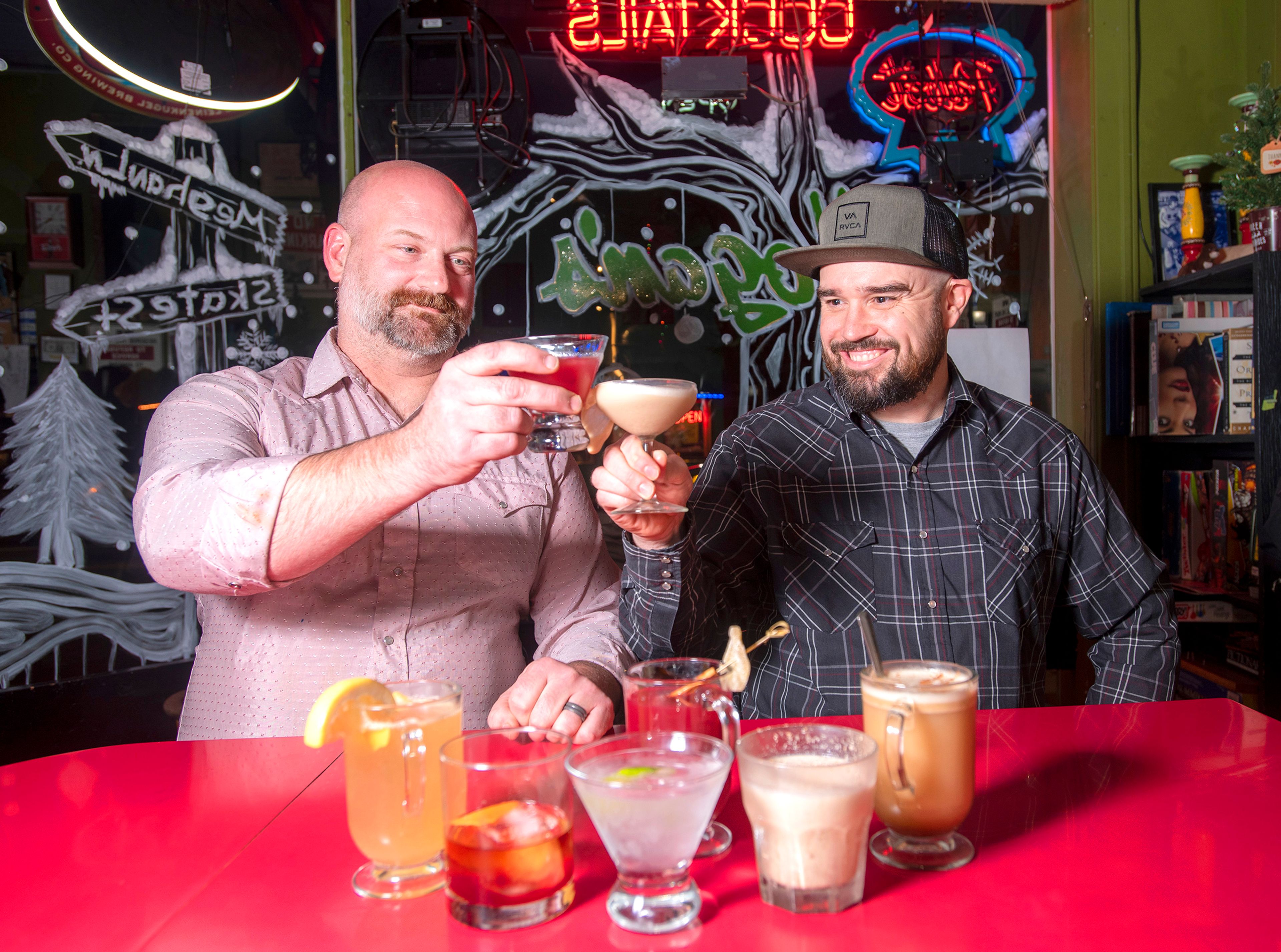 Hogan’s Pub co-owner/bartender Skate Pierce, left, and bartender Gary Burleson hoist drinks in December 2019. The men are business partners.