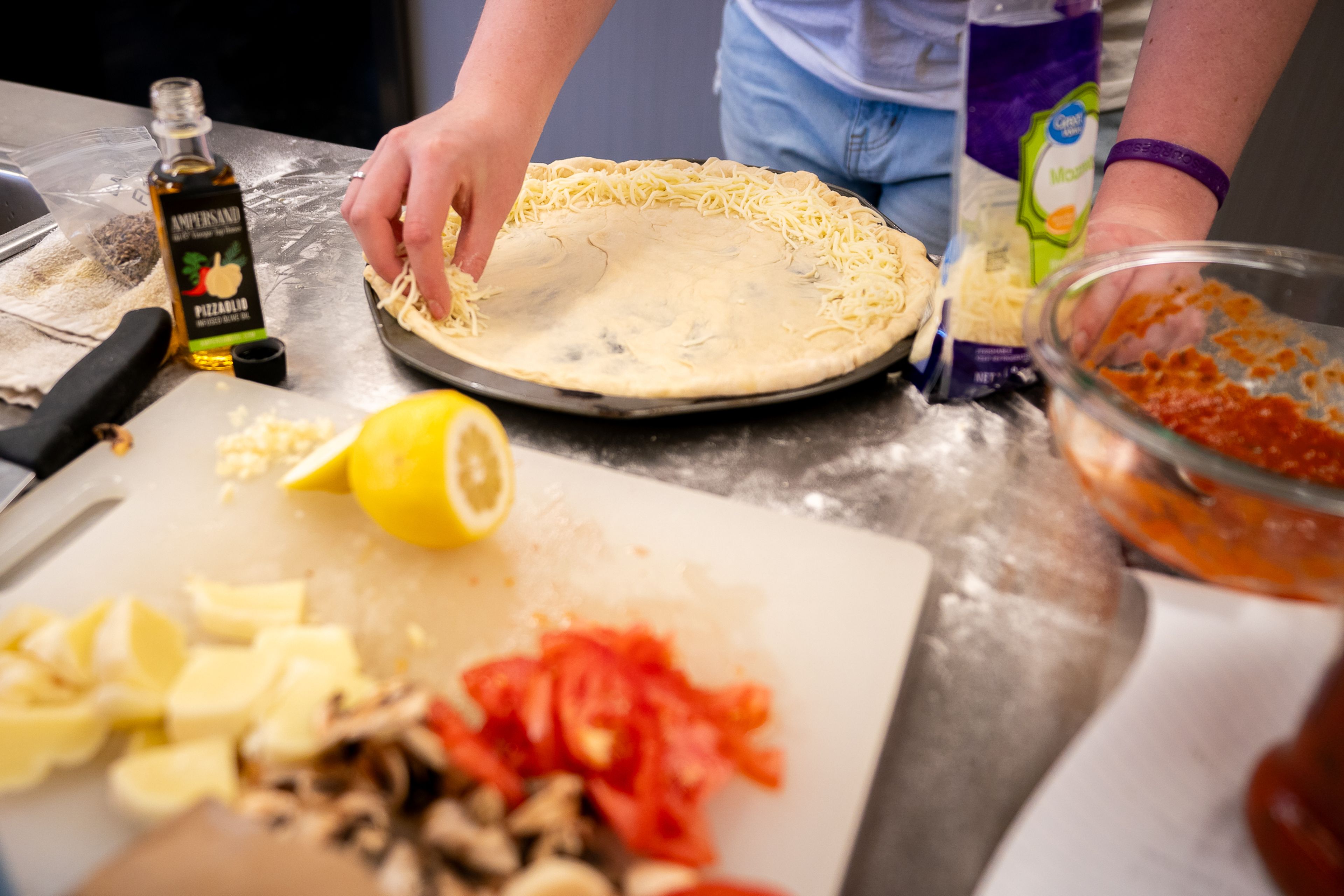 Hannah Wlash, 16, of Kellogg, sprinkles mozzarella cheese on the edge of her dough in order to make a stuffed crust during the final day of the 2023 Pizza-ology Camp on Wednesday at the Carmelita Spencer Food Laboratory in Moscow.