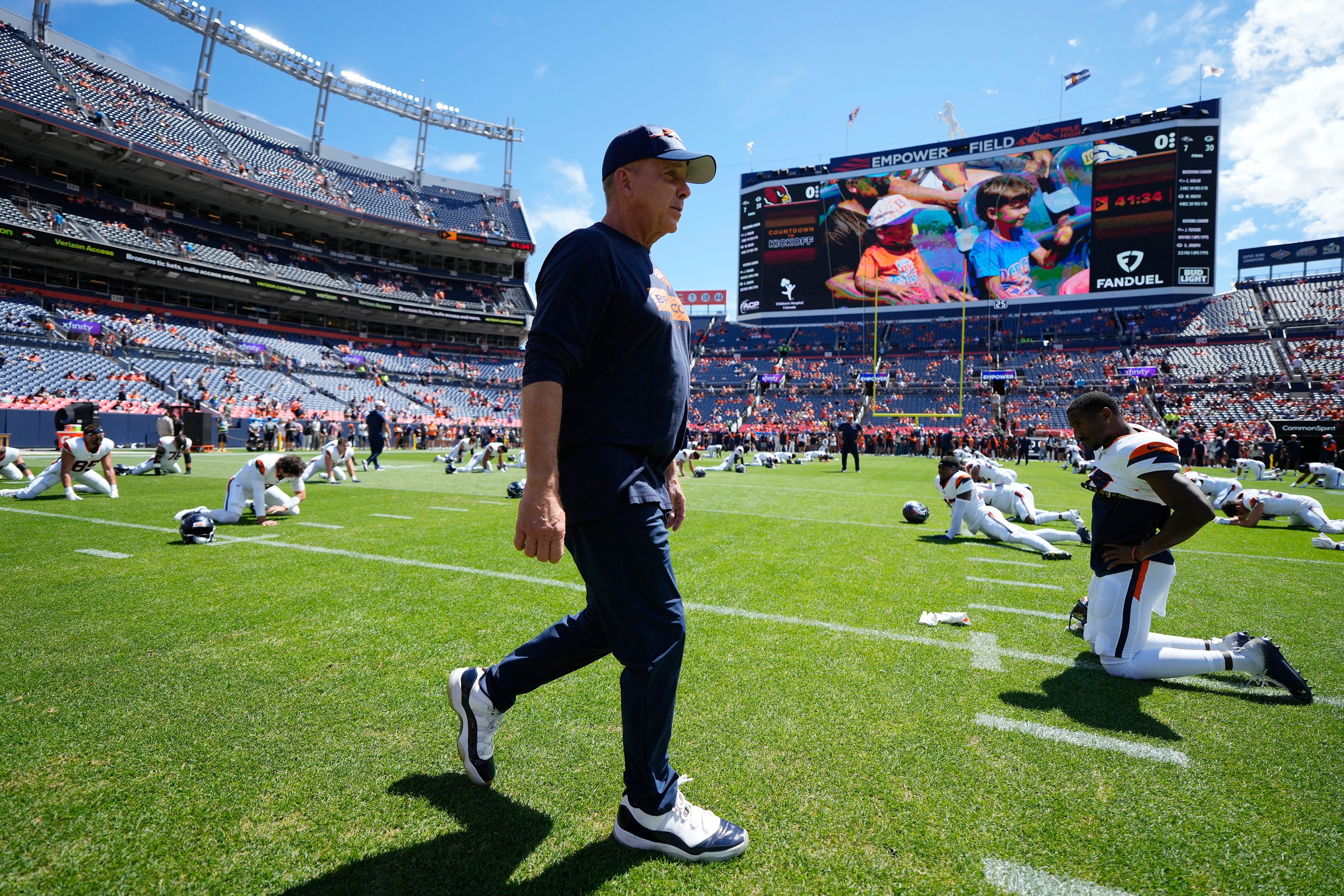 Denver Broncos head coach Sean Payton walks on the field as players warm up prior to a preseason NFL football game against the Arizona Cardinals, Sunday, Aug. 25, 2024, in Denver. (AP Photo/Jack Dempsey)