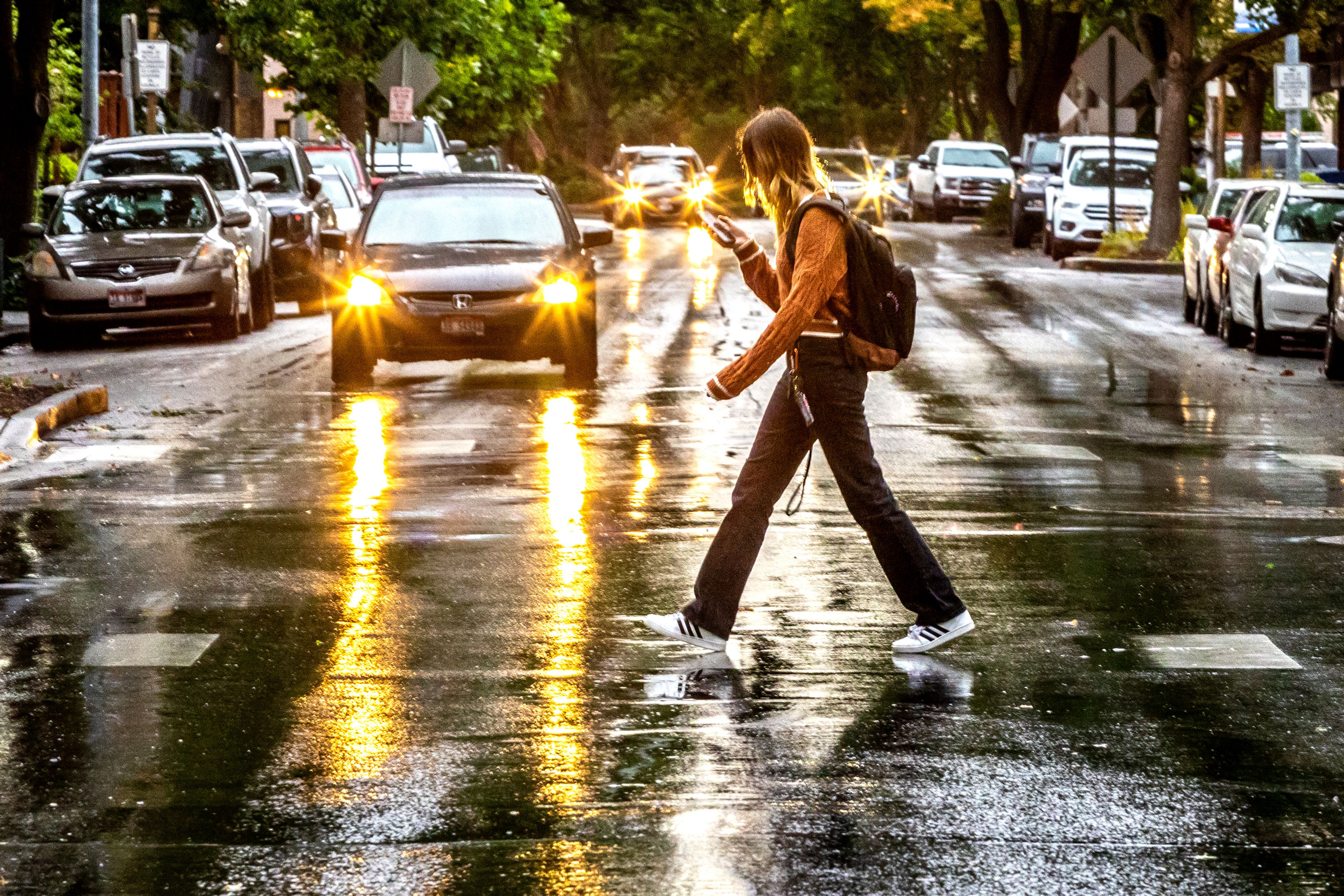 A person walks across Main Street as car headlights reflect off the wet pavement on Monday, Aug. 22, 2022. 