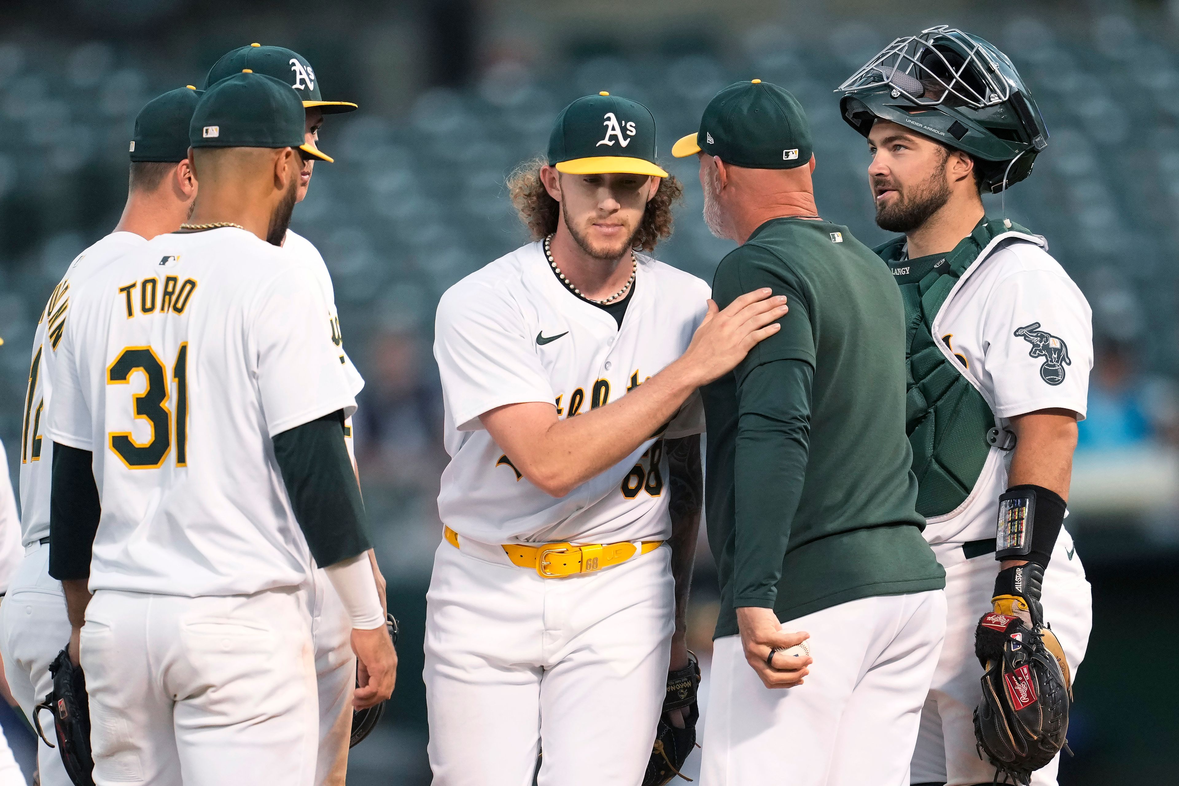 Oakland Athletics pitcher Joey Estes, middle, walks off the mound next to manager Mark Kotsay, middle right, during a pitching change in the seventh inning of the team's baseball game against the Seattle Mariners in Oakland, Calif., Wednesday, June 5, 2024. (AP Photo/Jeff Chiu)