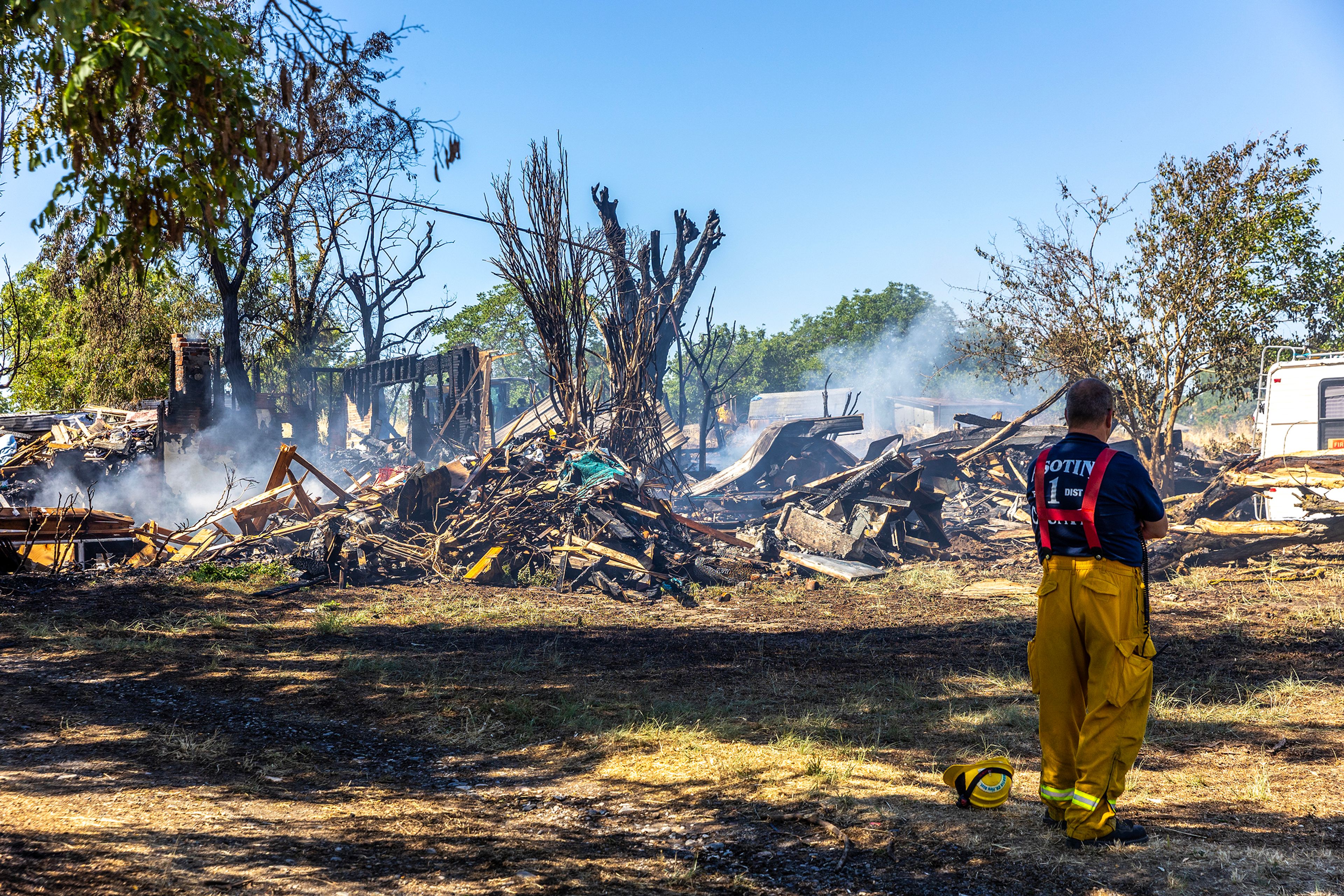 A firefighter looks on at the still smokings scene of a structure fire that was a total loss on Poplar Street on Friday in Clarkston.