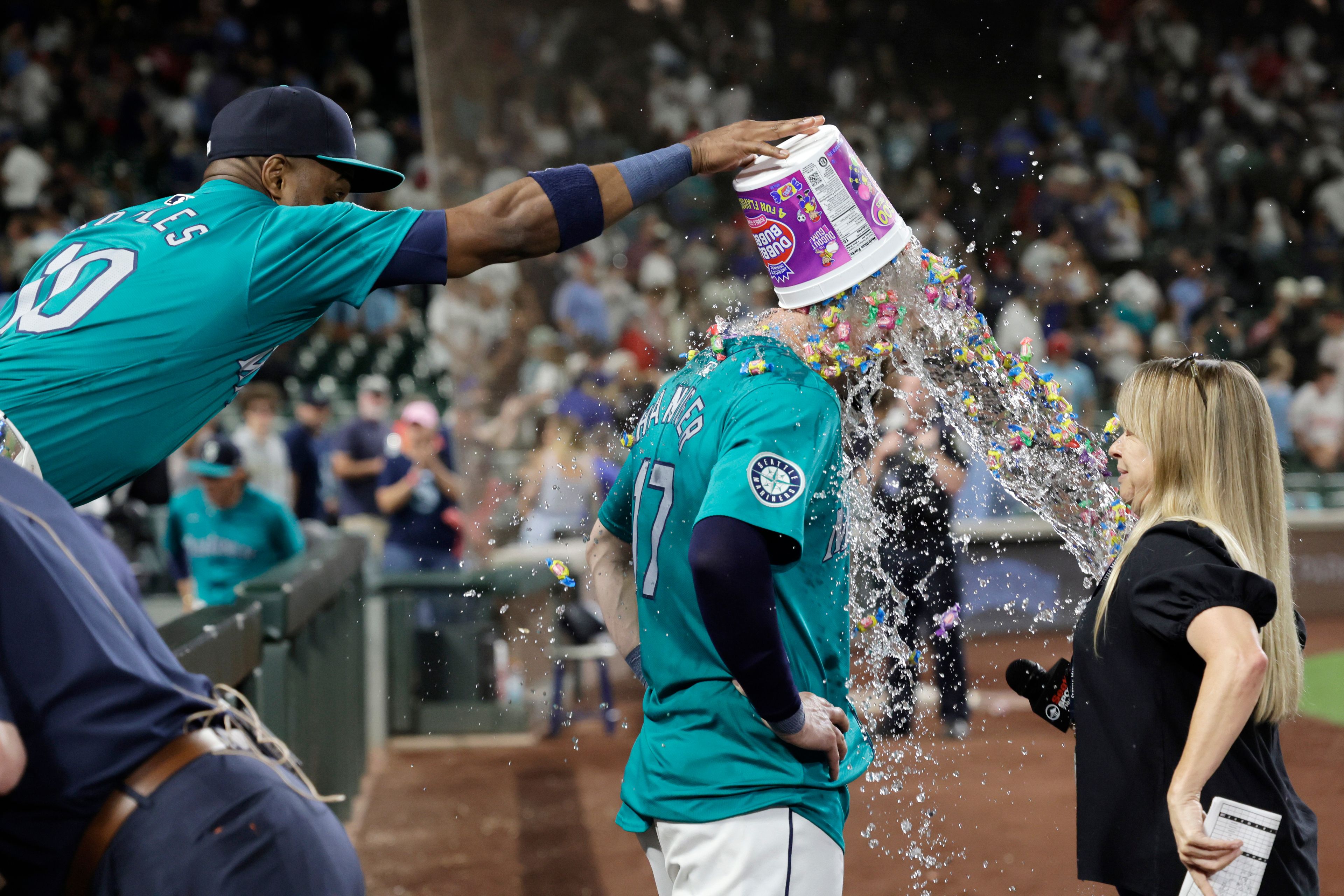 Seattle Mariners' Victor Robles, left, dumps a bucket of water and bubble gum on Mitch Haniger during an interview after his walk-off walk to win 6-5 against the Philadelphia Phillies in a baseball game Saturday, Aug. 3, 2024, in Seattle. (AP Photo/John Froschauer)