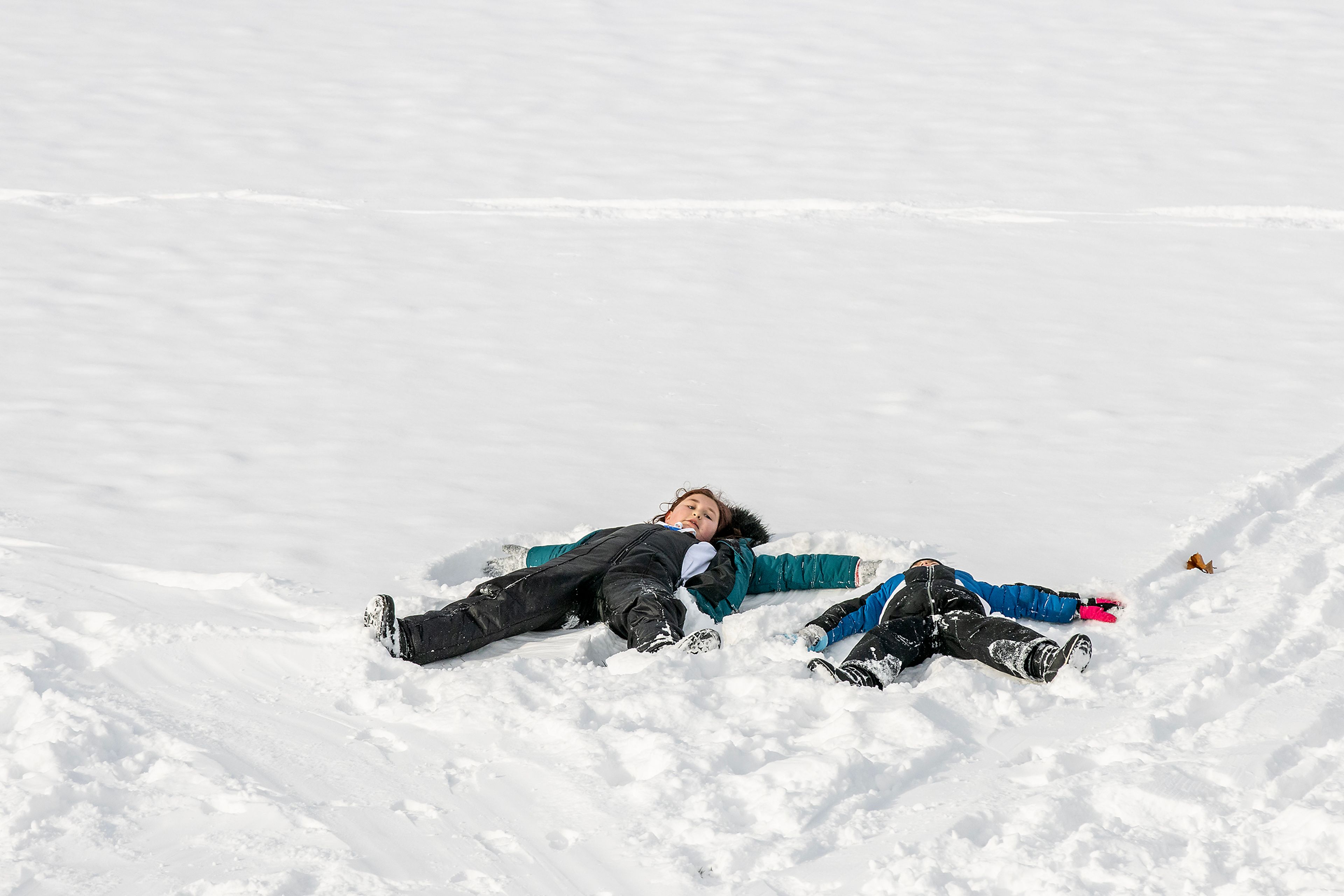 Avaline Phillips, 9, and Iver phillips, 5, both of Lewiston, take a rest to make some snow angels at the bottom of a hill while sledding at Sunset Park Friday in Lewiston.