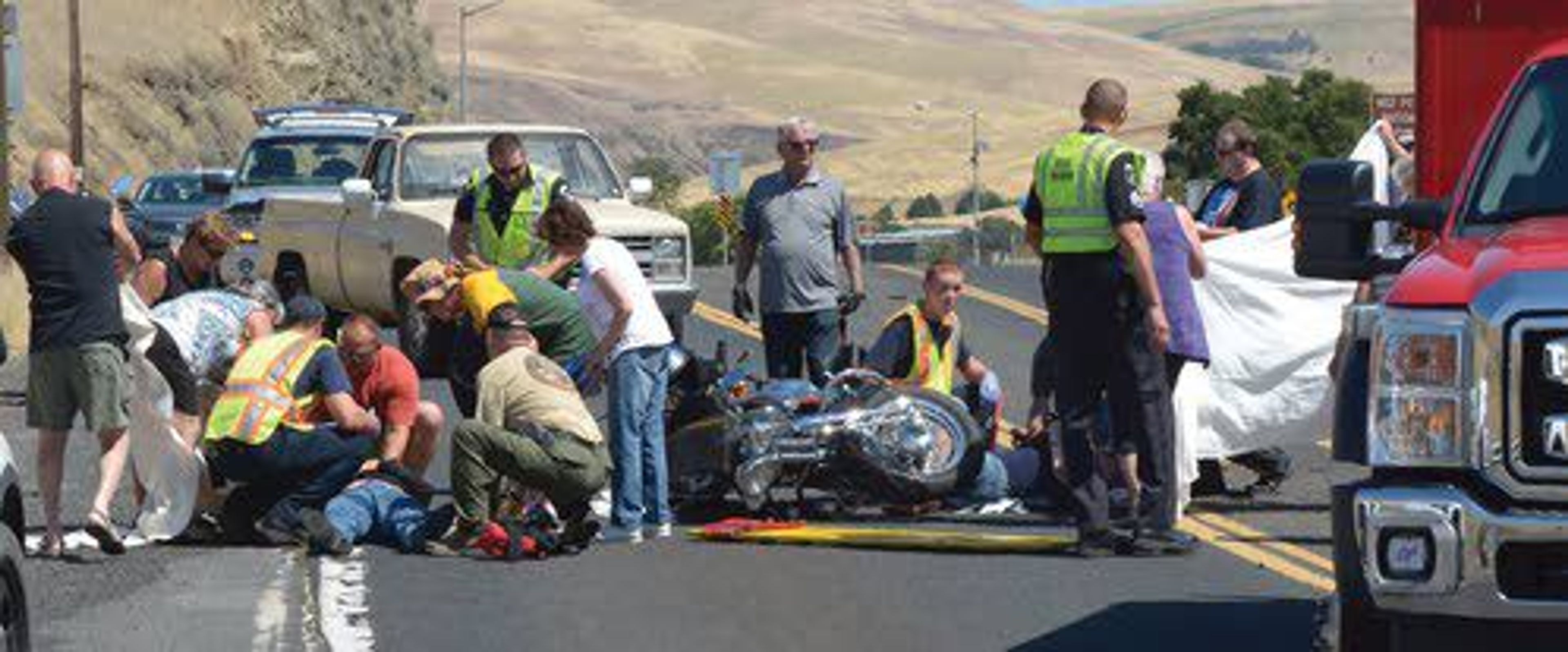 Bystanders shade the victims involved in a motorcycle accident on U.S. Highway 12 near the Spalding Bridge as Lewiston Fire Department first responders work to take the patients to St Joseph Regional Medical Center in Lewiston Saturday afternoon. For a video from the scene, go to the Tribune’s website at lmtribune.com.