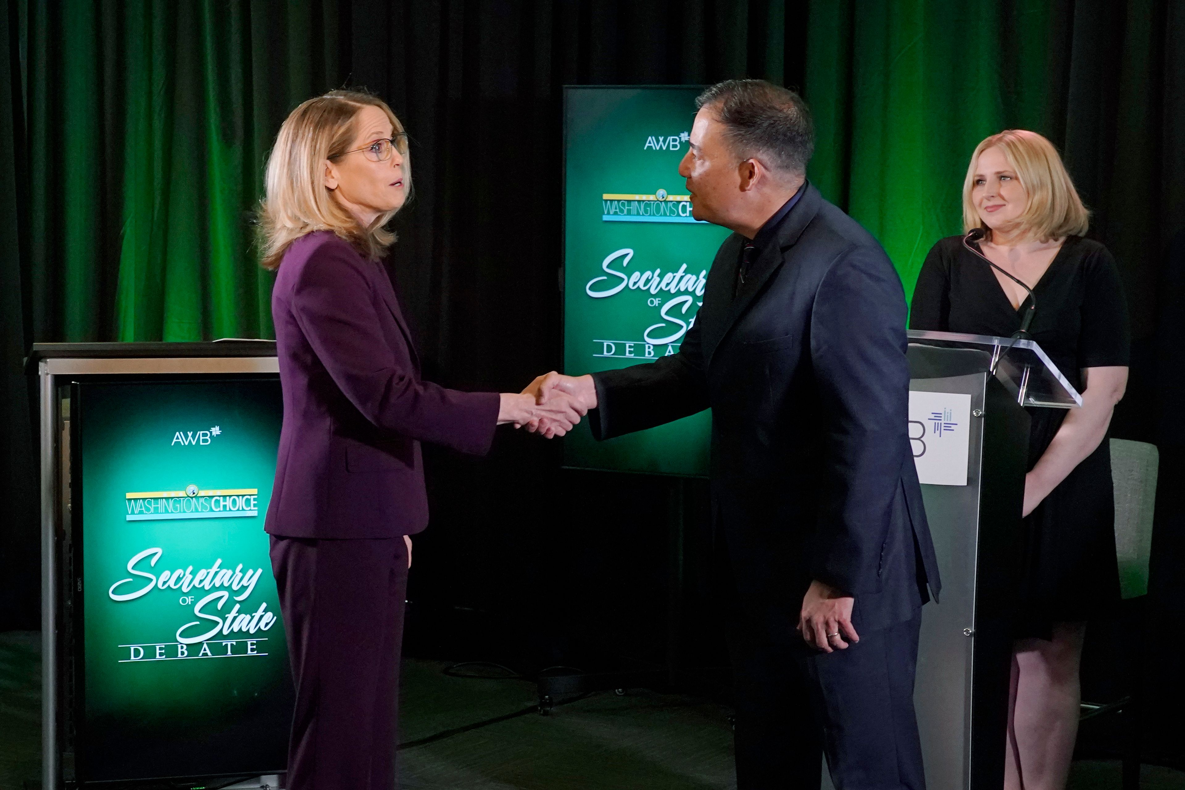 Washington Secretary of State Steve Hobbs, second from right, a Democrat, and Pierce County Auditor Julie Anderson, left, running as a nonpartisan, shake hands after taking part in a debate, Wednesday, Aug. 17, 2022, in Olympia, Wash., as moderator Melissa Santos, right, of Axios Local, looks on. Hobbs and Anderson are seeking to fill the remaining two years of the term of Republican Secretary of State Kim Wyman, who left to take a key election security job in the Biden administration. (AP Photo/Ted S. Warren)