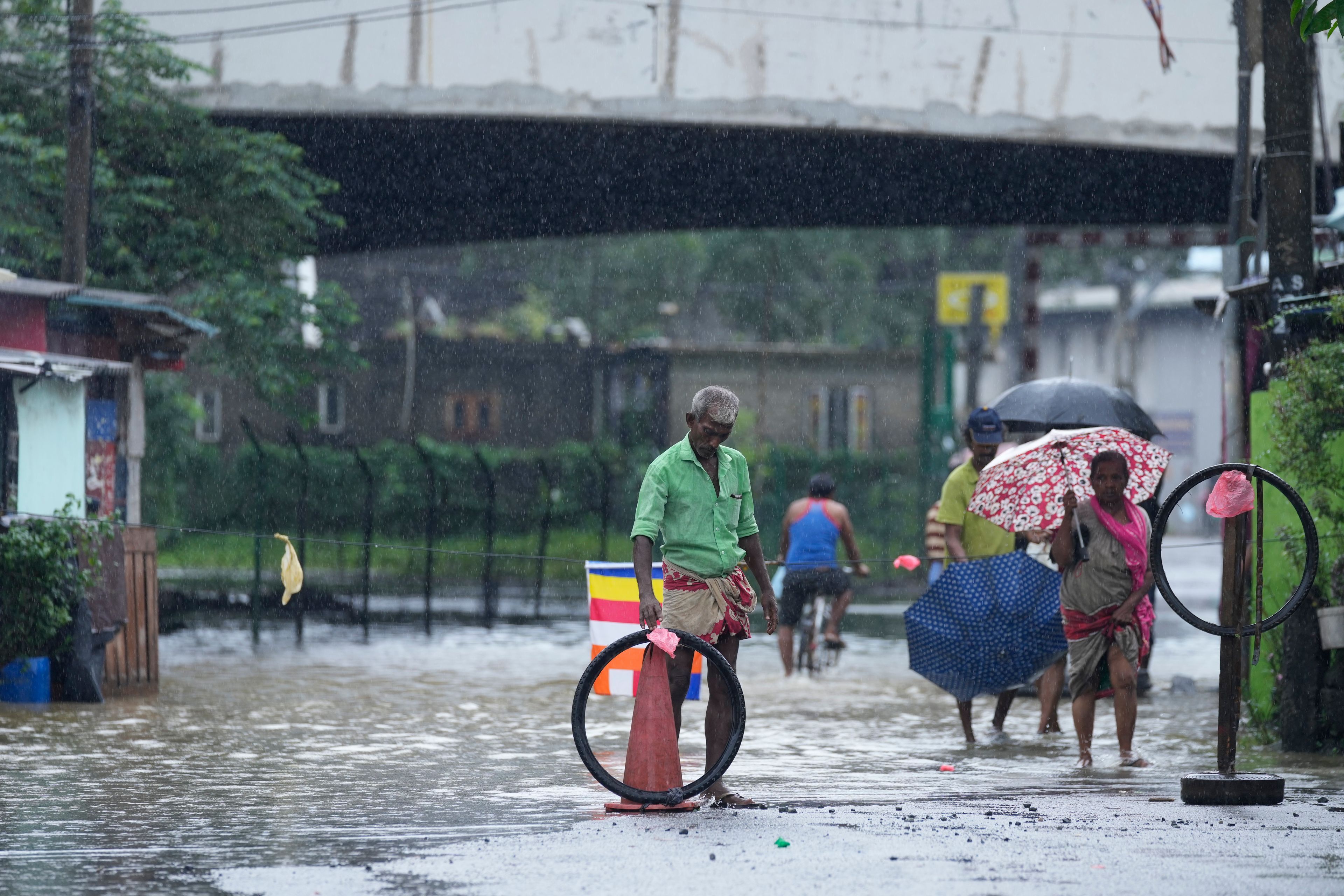 People wade through flood waters in Kelaniya, a suburb of Colombo, Sri Lanka, Monday, June 3, 2024. Sri Lanka closed schools on Monday as heavy rains triggered floods and mudslides in many parts of the island nation, killing at least 10 people while six others have gone missing, officials said.