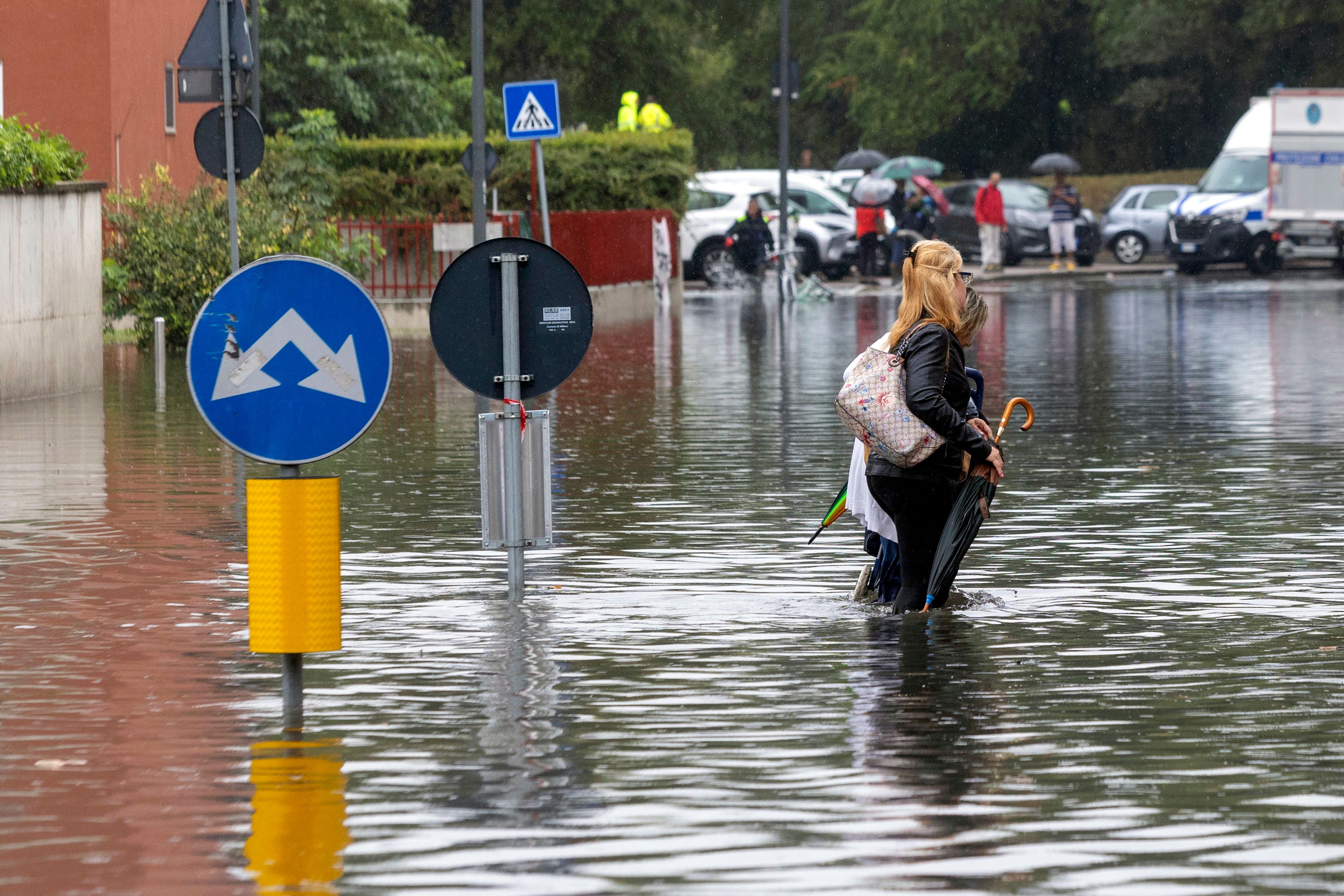 Two women wade through floodwater caused by heavy rain in a street in Milan, Italy, Thursday Sept. 5, 2024.