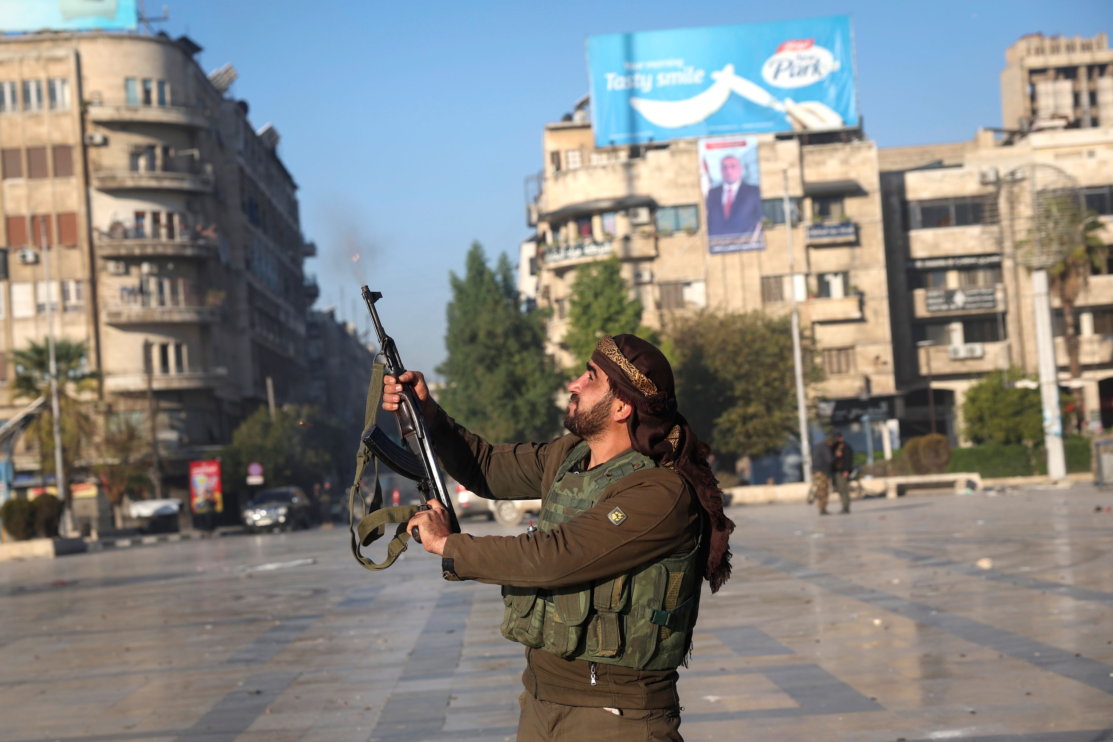 A Syrian opposition fighter shoots in the air in downtown Aleppo, Syria, Saturday Nov. 30, 2024. (AP Photo/Ghaith Alsayed)