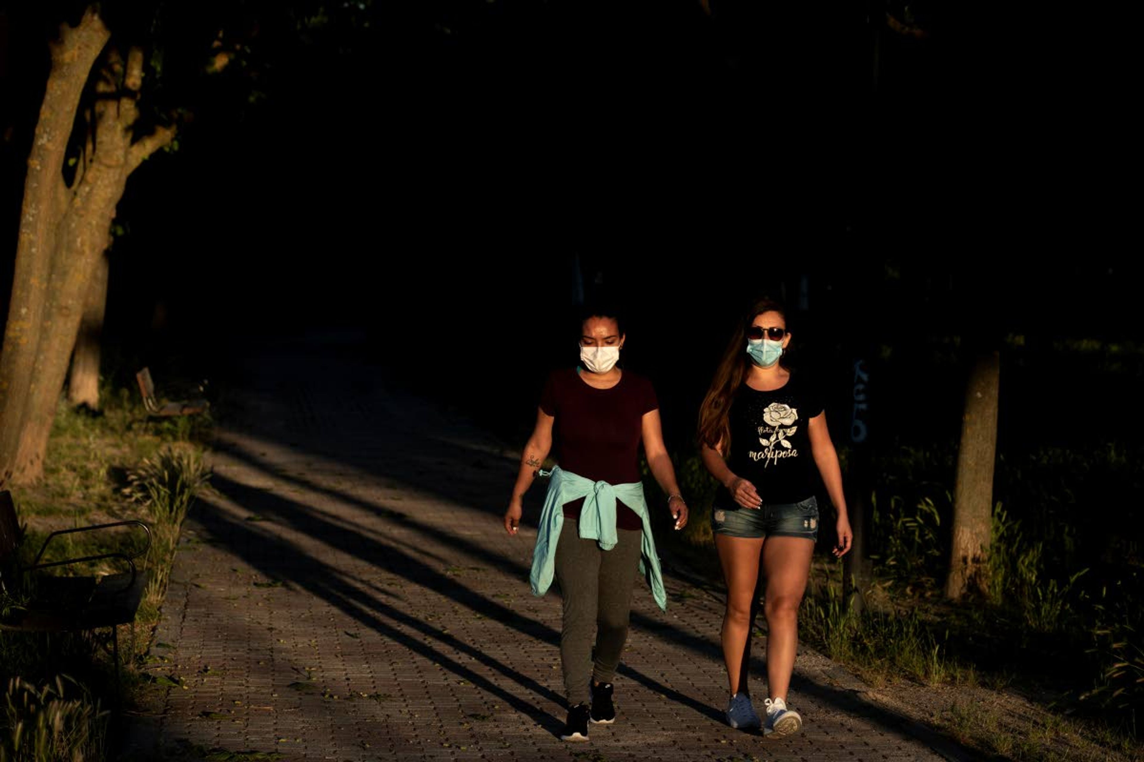 People wearing face masks to combat the spread of coronavirus walk in a public park in Madrid, Spain, Wednesday, May 6, 2020. Spain has this week started to roll back from a lockdown in place since mid-March, one of the world's strictest. (AP Photo/Manu Fernandez)