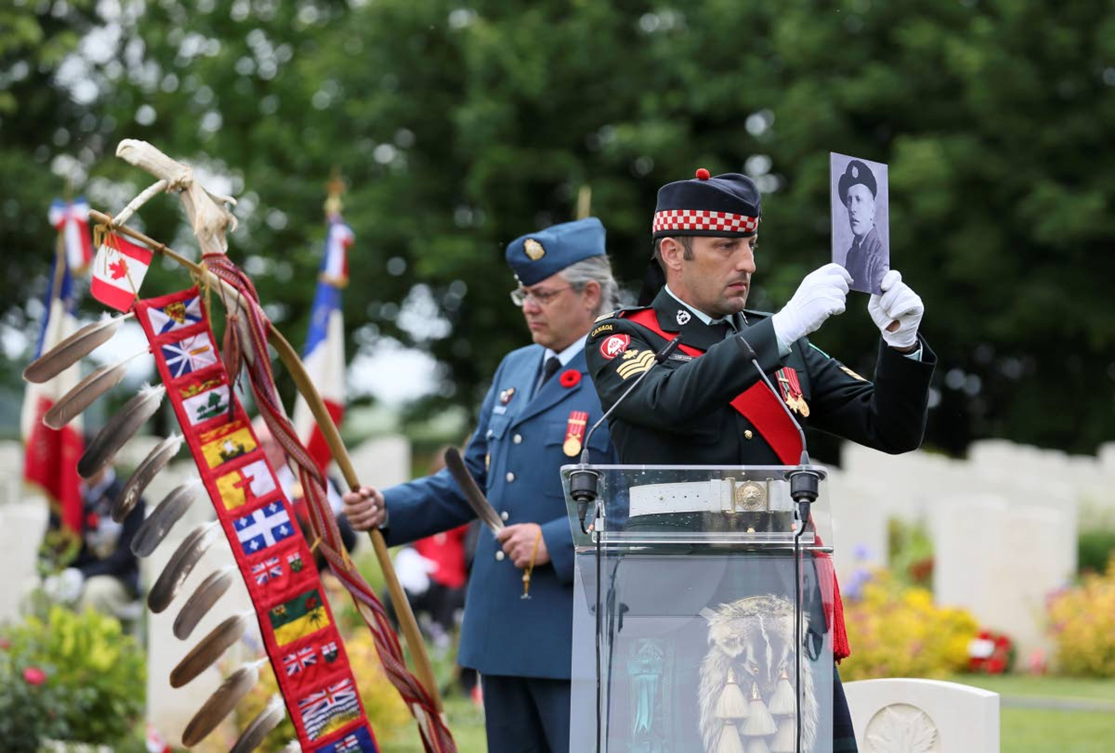 A member of the Canadian Armed Forces holds a photo of a Canadian World War II soldier during a ceremony at the Beny-sur-Mer Canadian War Cemetery in Reviers, Normandy, France, Wednesday, June 5, 2019. A ceremony was held on Wednesday for Canadians who fell on the beaches and in the bitter bridgehead battles of Normandy during World War II. (AP Photo/David Vincent)