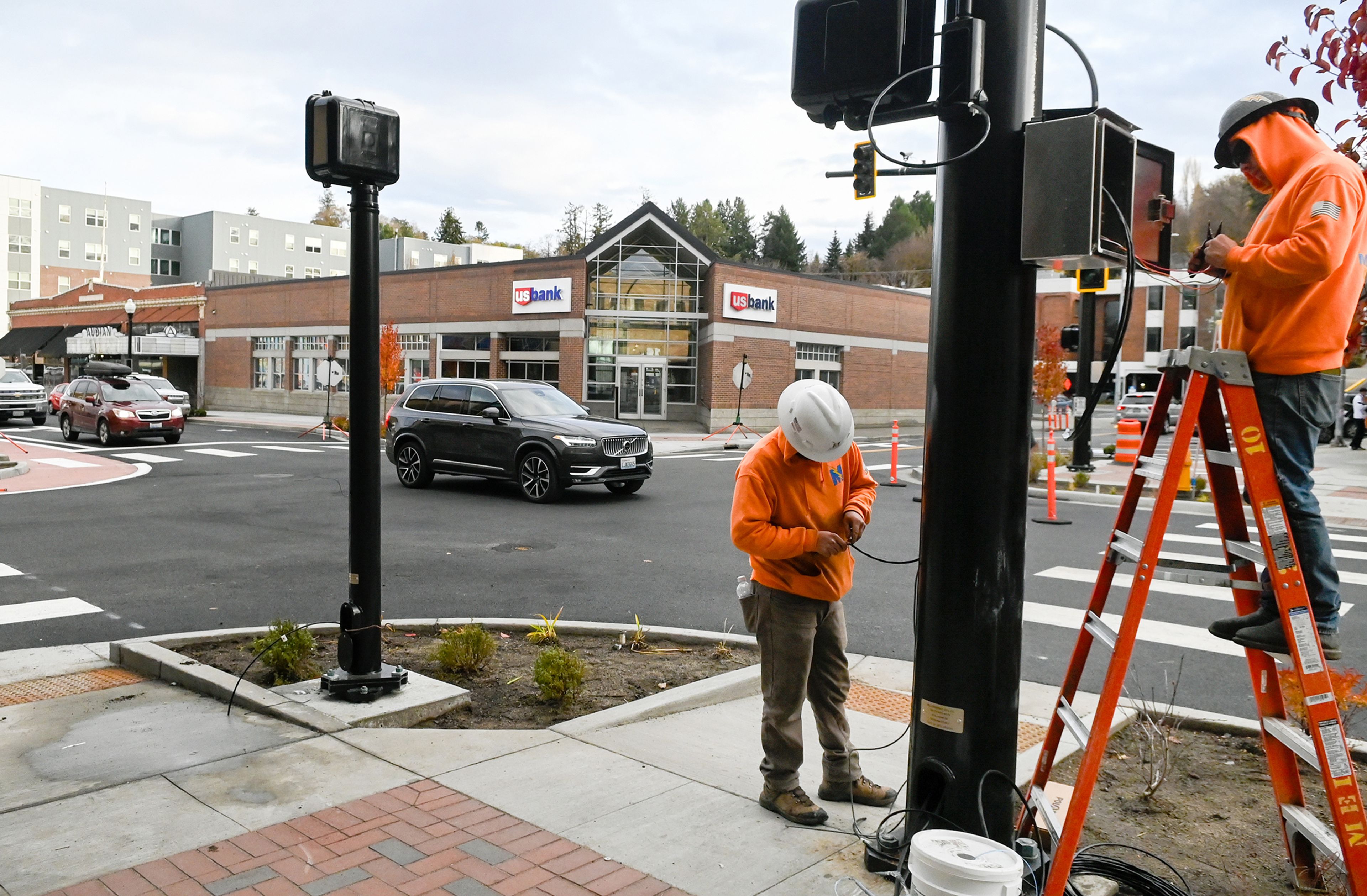 Cars move down Main Street after the road partially reopened to traffic Thursday in Pullman. A crew with Midland Electric works on a street light as construction continues in areas of the street.