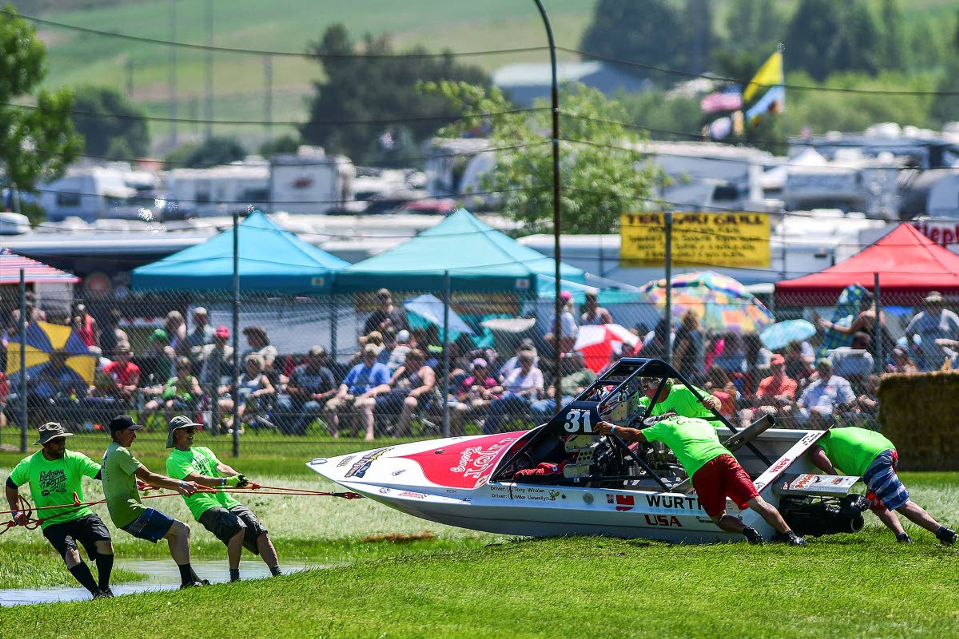 The Webb's Slough crew pulls in the YNot racing boat after it drifted onto the grass during a 400 Class qualifying run during the Webb's Slough sprint boat races in St. John on Saturday.