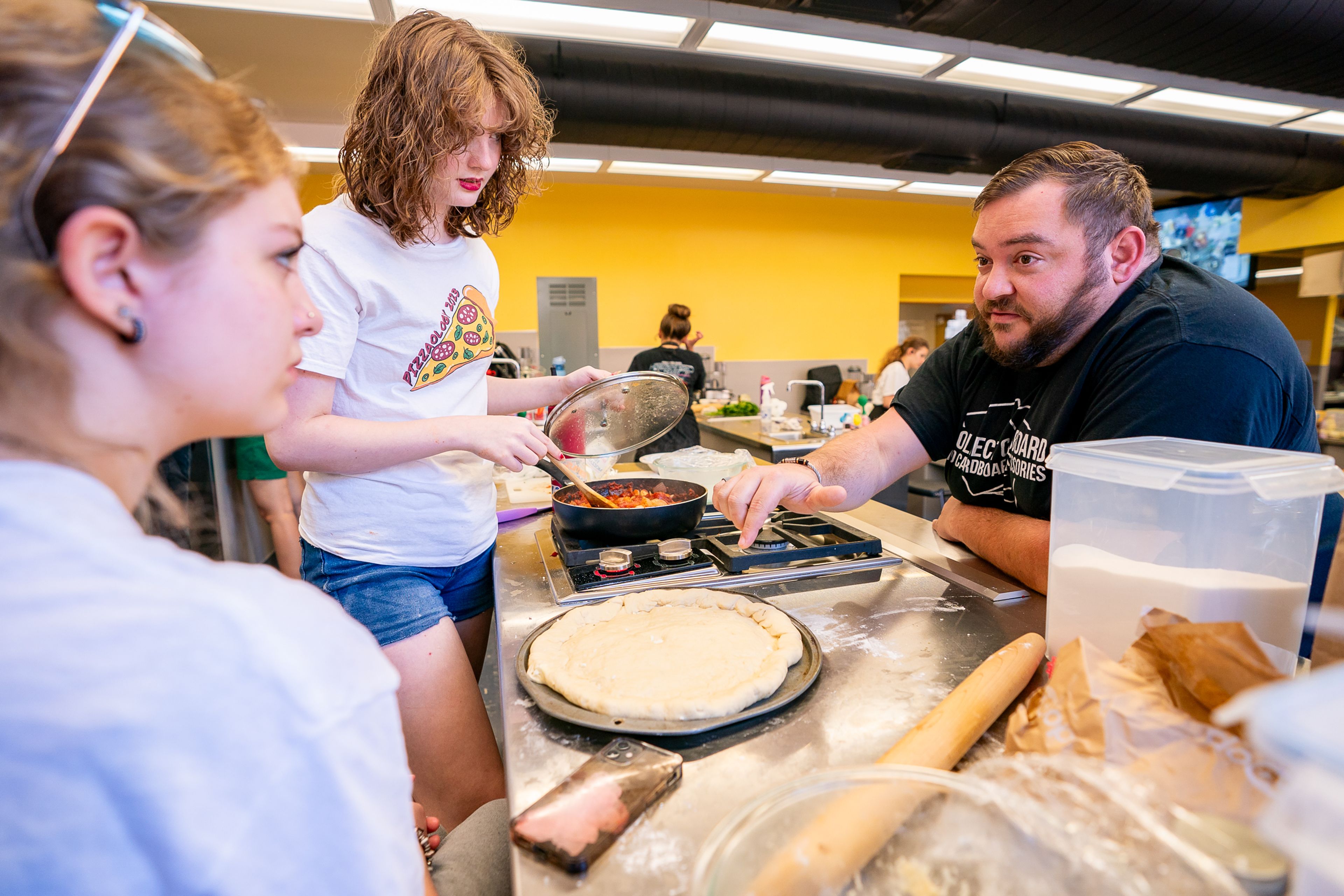 Kyla Darg, left, 16, and Xai Carey, center, 15, both of Wallace, listen as Michelin-star chef Steven Frank shows them how to make a crispy crust during the final day of the 2023 Pizza-ology Camp on Wednesday at the Carmelita Spencer Food Laboratory in Moscow.