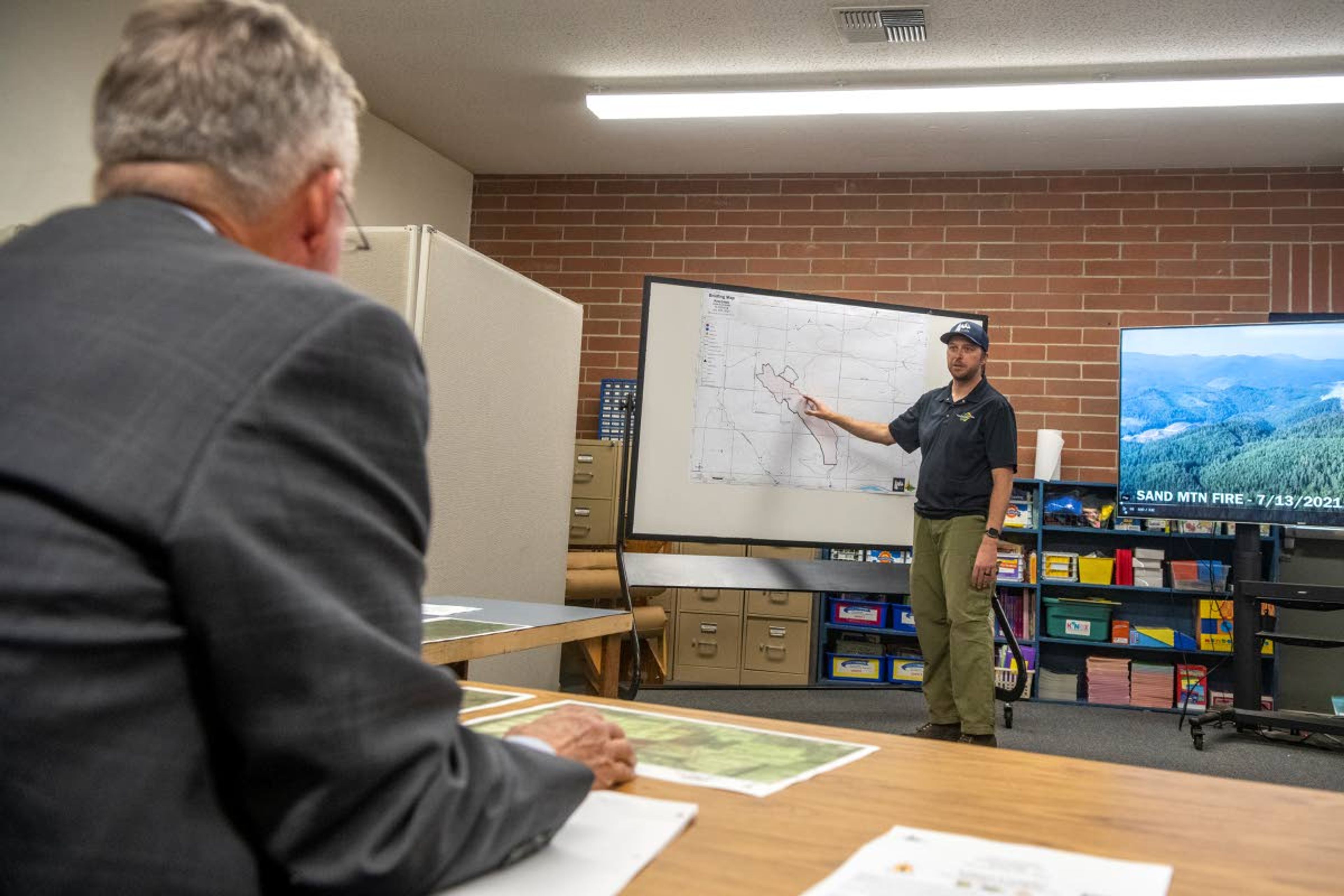 Incident Command Mike McManus, of the Type 3 North Idaho Incident Management team, briefs Idaho Gov. Brad Little at Deary High School on Thursday morning about the crew’s ongoing wildfire battles against the Sand Mountain Fire and Pine Creek Fire.