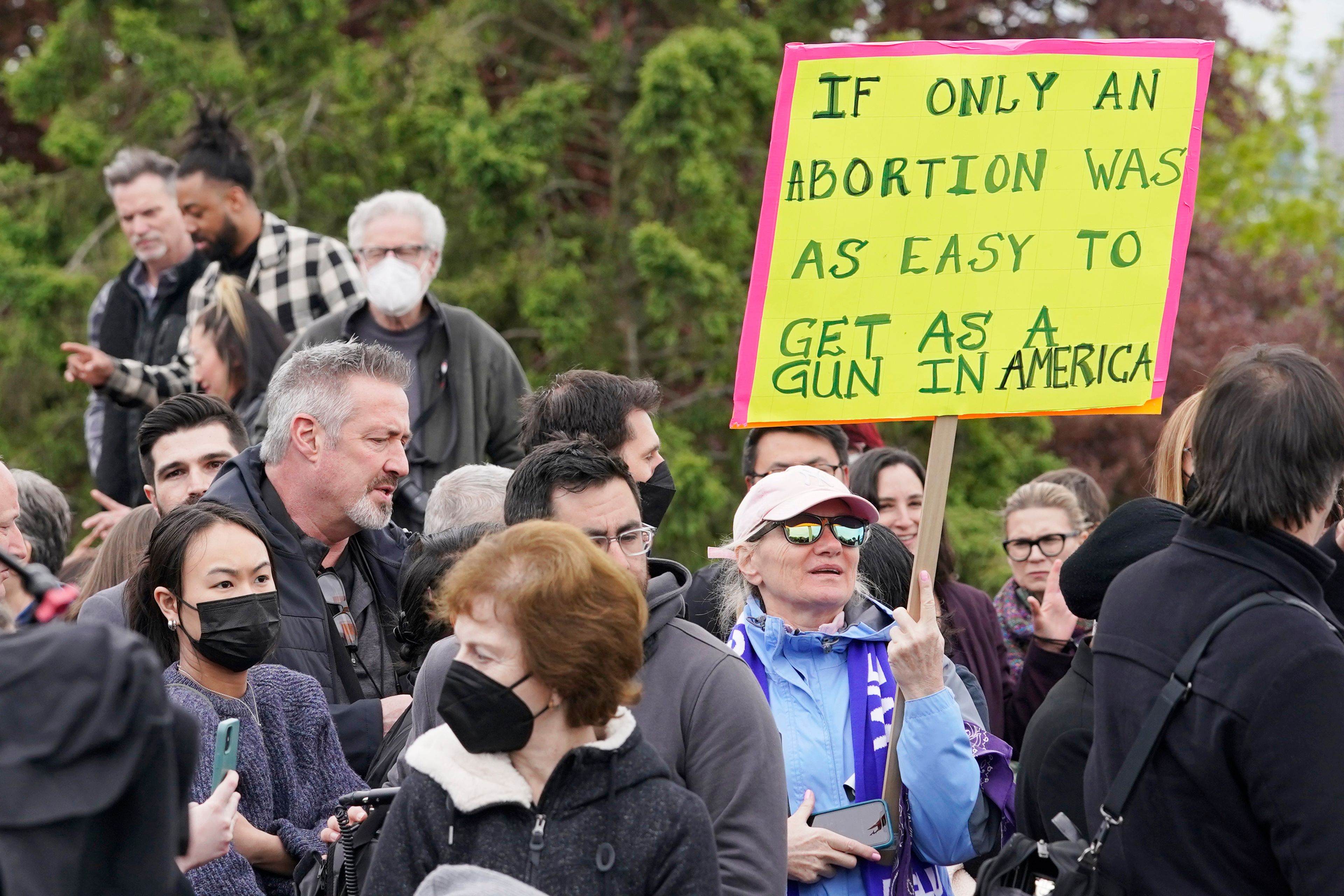 A person holds a sign comparing access to abortions to purchasing guns, Tuesday, May 3, 2022, during a rally at a park in Seattle in support of abortion rights. (AP Photo/Ted S. Warren)