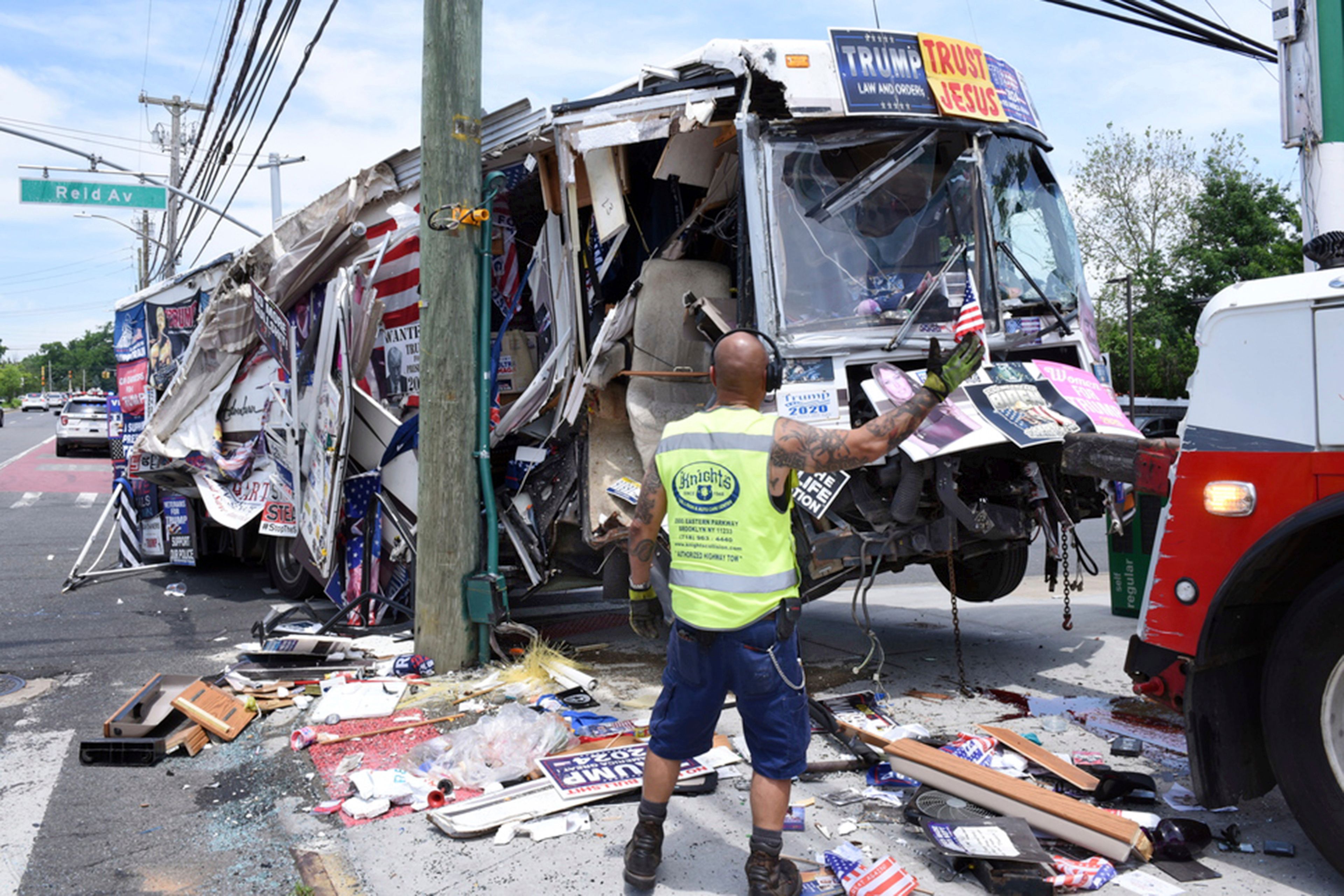 The remains of a bus owned by a couple that sold pro-Donald Trump merchandise is towed, Sunday, June 2, 2024, in the Staten Island borough of New York, after it crashed into several street signs and utility poles. Donna Eiden, who had been living in the bus with her husband, Rocky Granata, and their cat, said that she was sleeping inside the parked vehicle when when it began to roll crashing into signs and poles in its path.