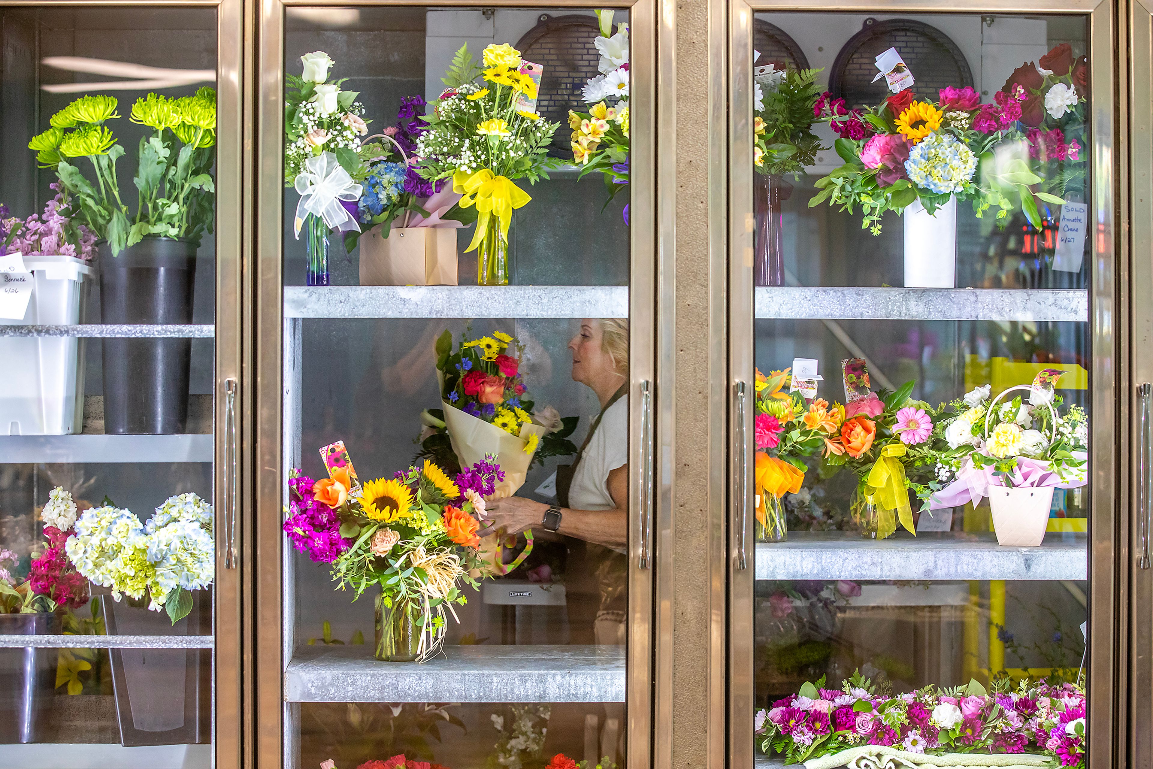 Judy Nuxoll carries a flower arrangement at Hills Valley Floral Tuesday in Lewiston.