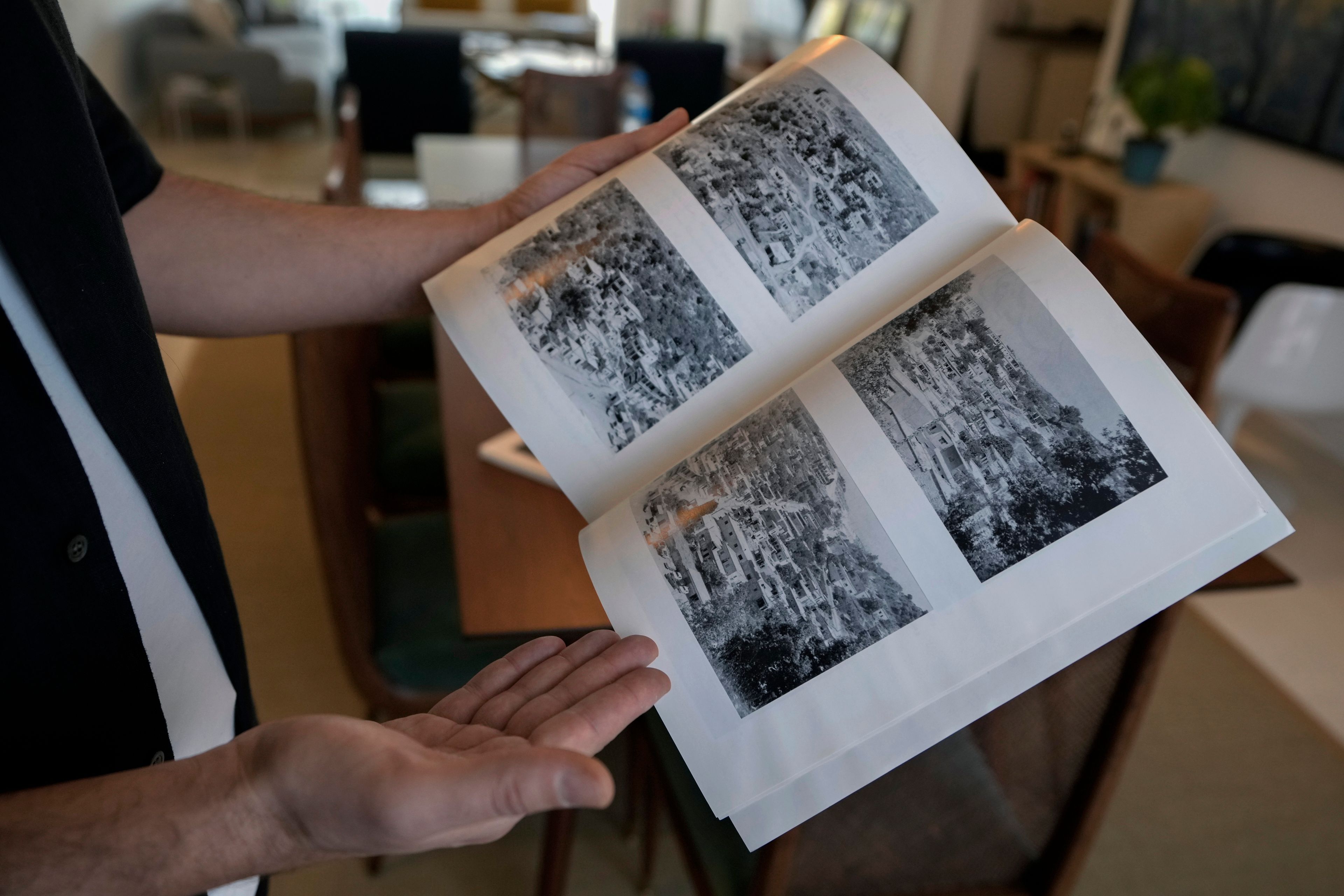 Lubnan Baalbaki shows pictures of Odeisseh village taken by his late father, during an interview with The Associated Press at his house in Geitawi, Beirut, Lebanon, Thursday, Oct. 31, 2024. (AP Photo/Bilal Hussein)