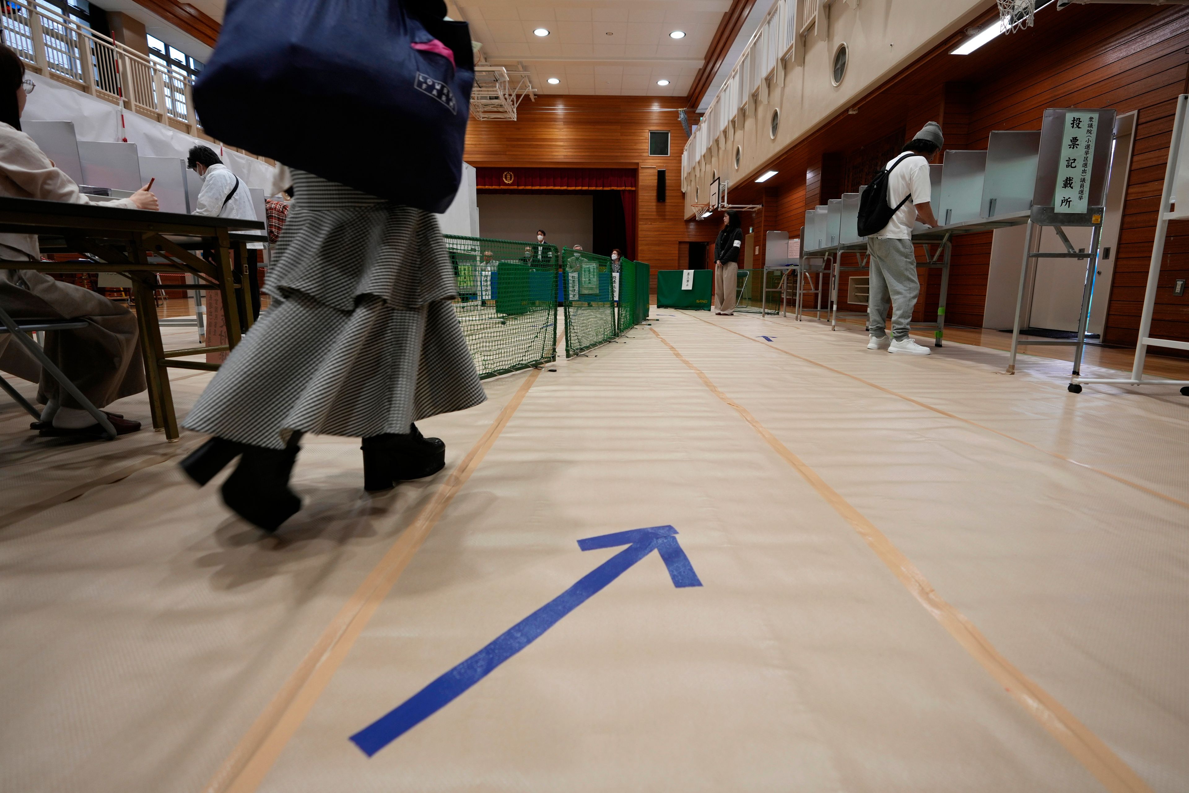 A woman walks towards voting booths at a polling station for Japan's lower house election in Tokyo, Japan, Sunday, Oct. 27, 2024. (AP Photo/Hiro Komae)