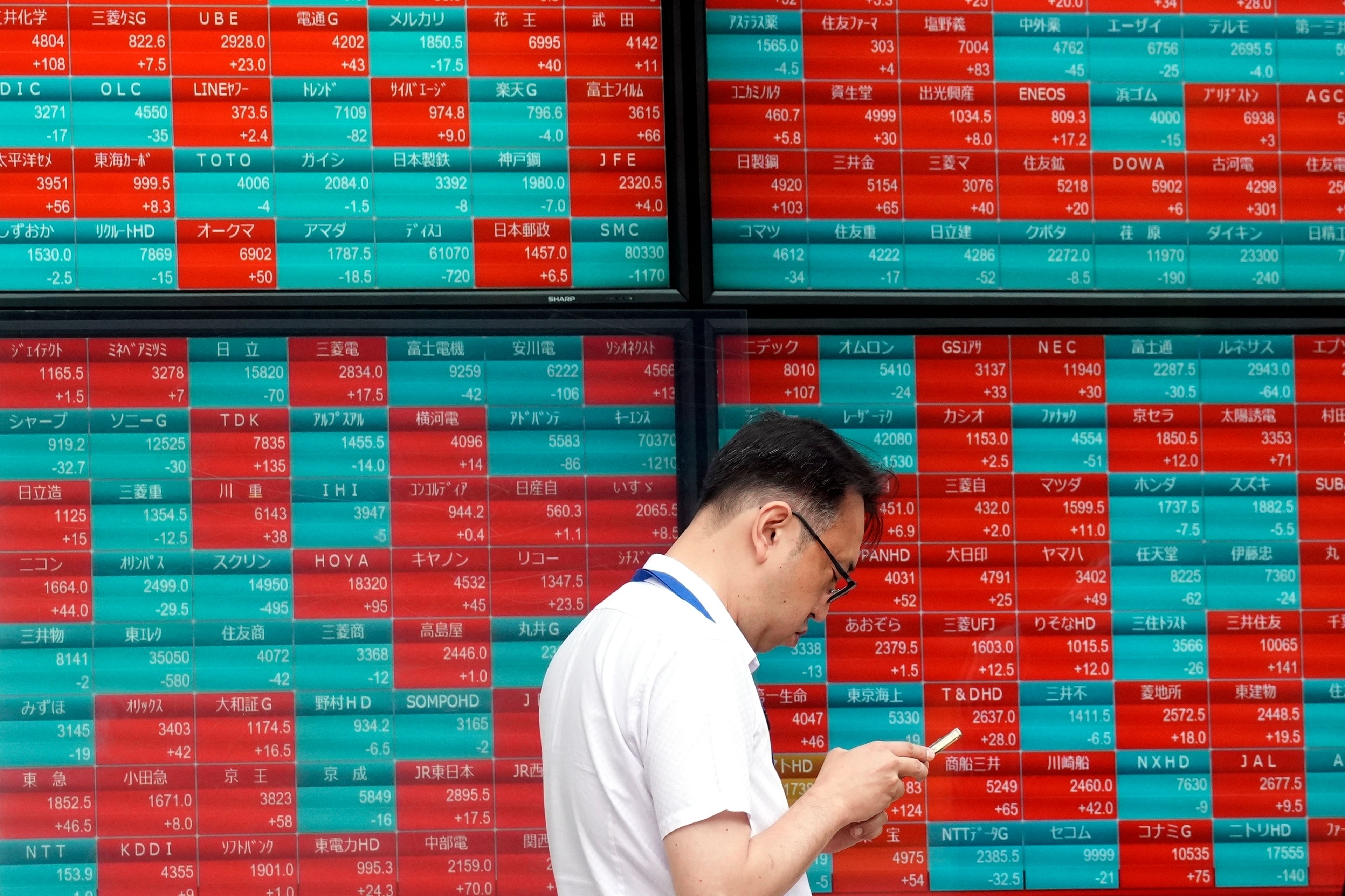 FILE - A person stands in front of an electronic stock board showing Japan's Nikkei index at a securities firm in Tokyo, on May 28, 2024. Asian shares traded mixed Wednesday, June 5, 2024, as investors weighed recent data highlighting a slowing U.S. economy that offers both upsides and downsides for Wall Street.