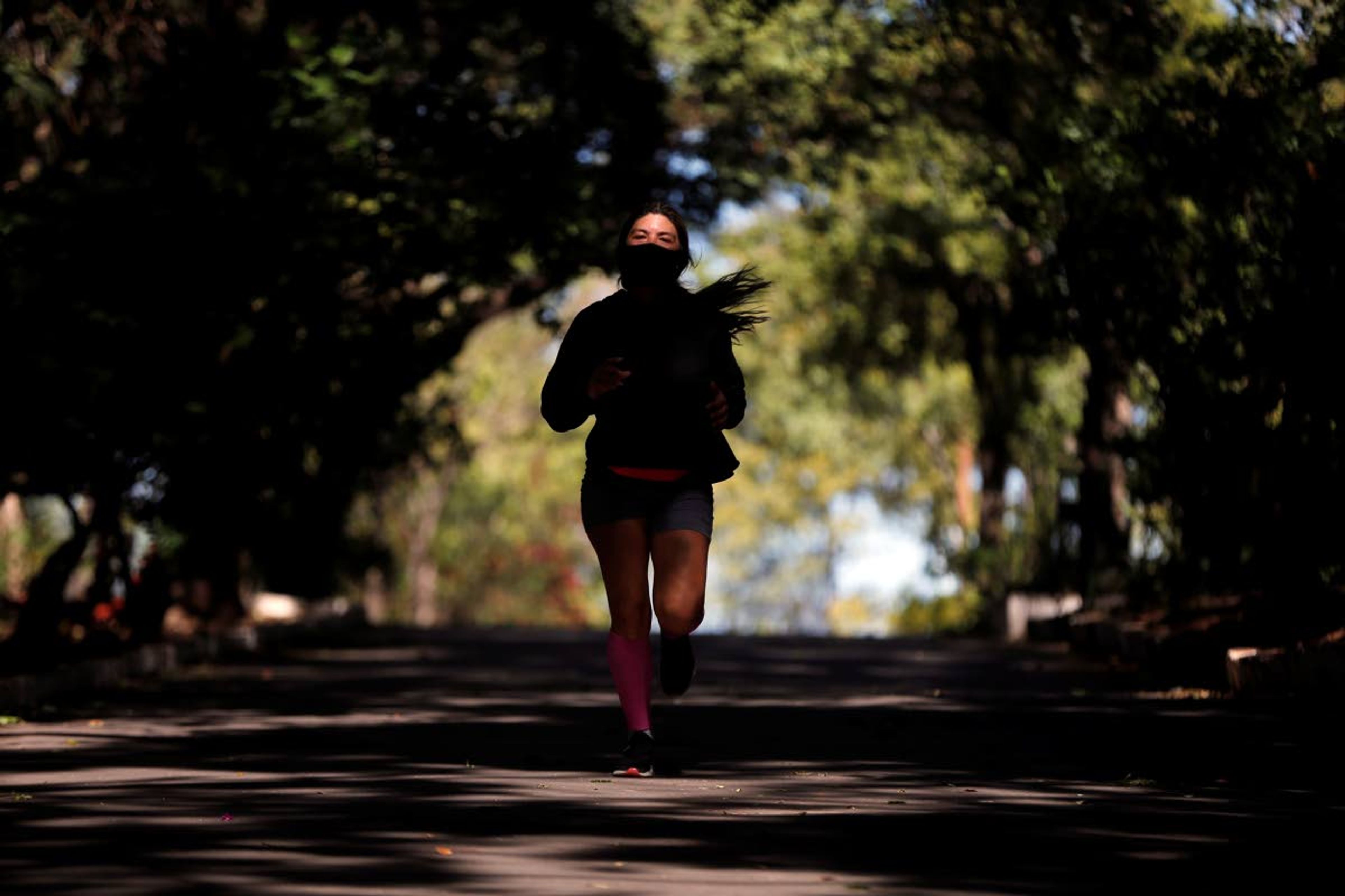 Susana Morales, a 45-year-old architect, jogs wearing a mask to protect herself from the new coronavirus, past a recently reopened park in Asuncion, Paraguay, Wednesday, May 6, 2020. The government authorized the reopening of some parks and businesses under a plan coined “Intelligent quarantine,” amid the spread of COVID-19. (AP Photo/Jorge Saenz)