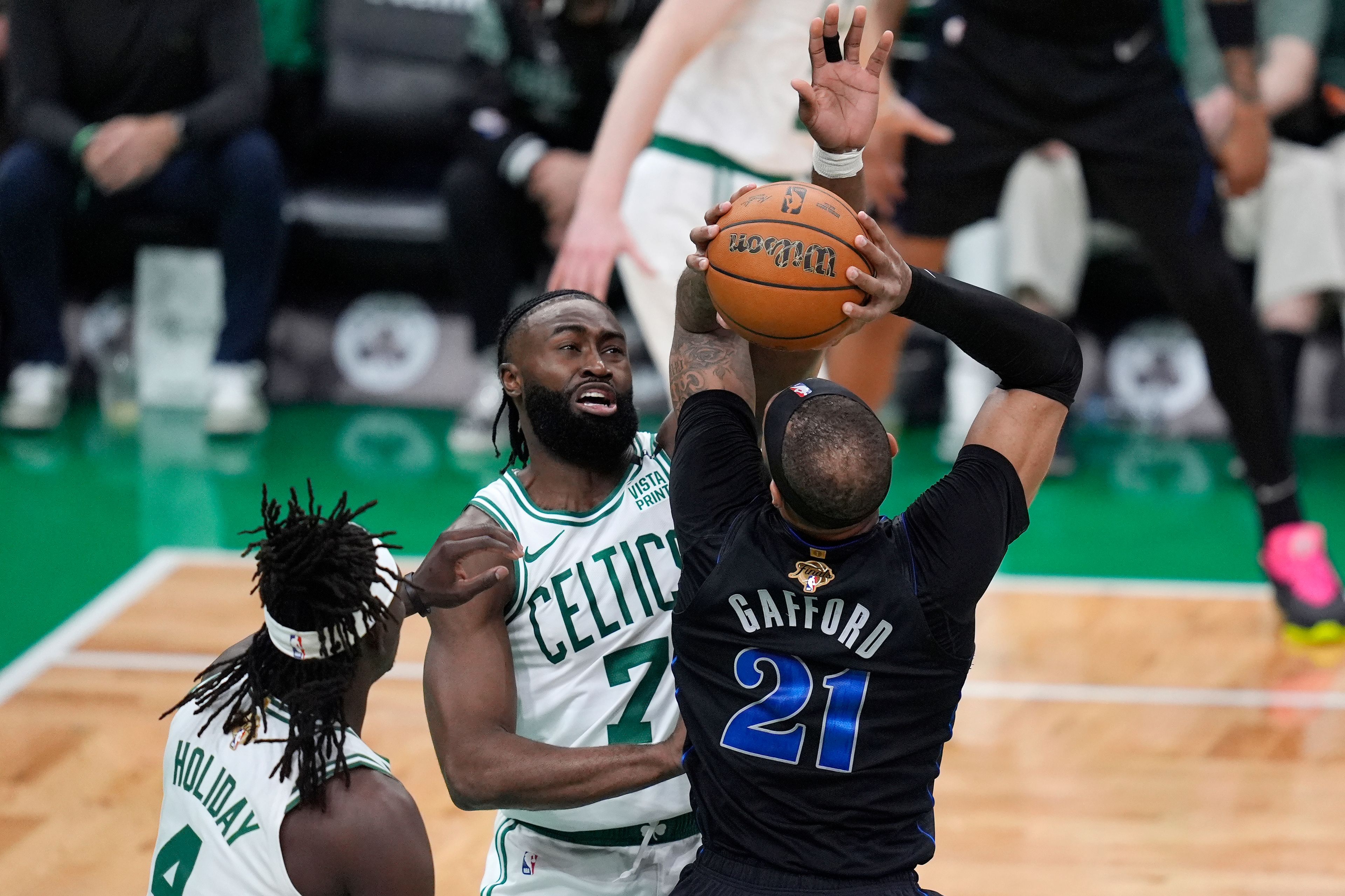 Dallas Mavericks center Daniel Gafford (21) shoots as Boston Celtics guard Jaylen Brown (7) and guard Jrue Holiday (4) defend during the first half of Game 1 of basketball's NBA Finals on Thursday, June 6, 2024, in Boston.