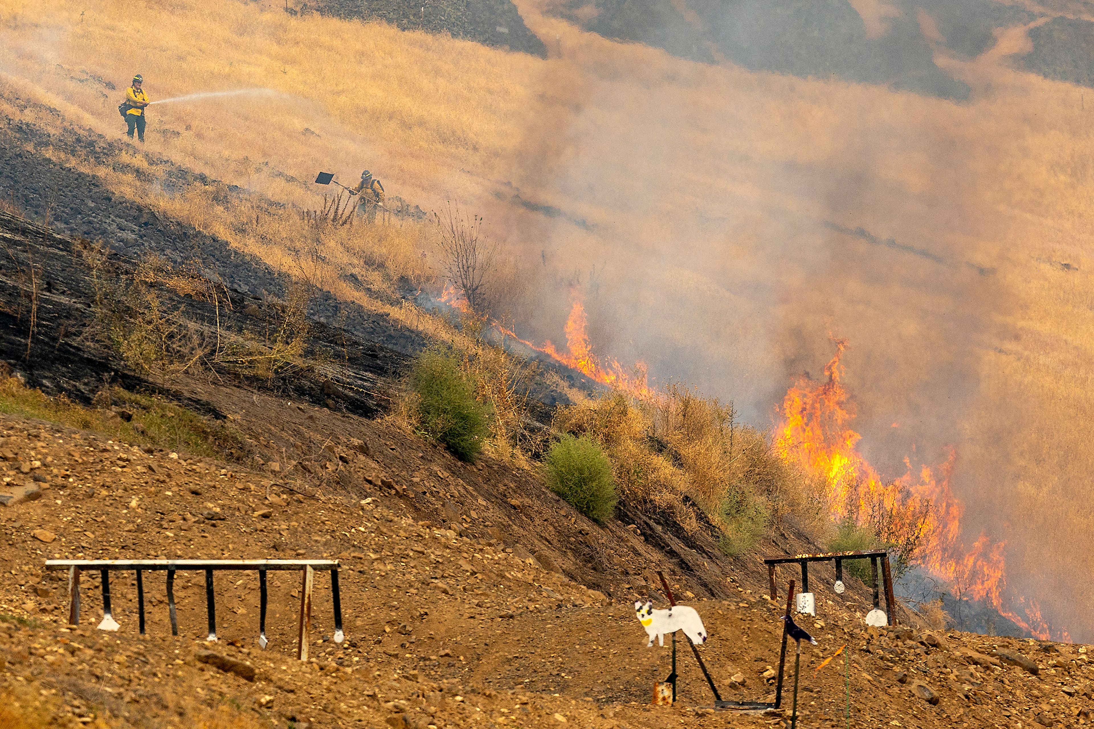 Firefighters work to put out a grassland fire Tuesday behind the Lewis-Clark Wildlife Club shooting range off South Tom Beall Road near Lapwai.